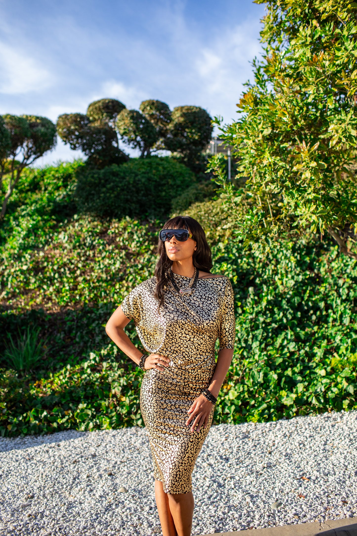 An angle dress made from a gold leopard foil-detailed stretchy jersey, featuring a fitted pencil skirt and light ruching at the hip. The angled sleeves can be arranged for a peek of shoulder and bra strap.