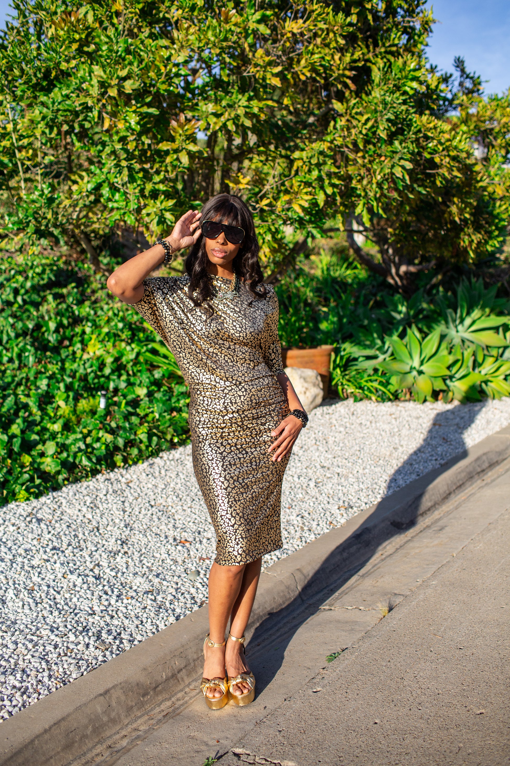 An angle dress made from a gold leopard foil-detailed stretchy jersey, featuring a fitted pencil skirt and light ruching at the hip. The angled sleeves can be arranged for a peek of shoulder and bra strap.
