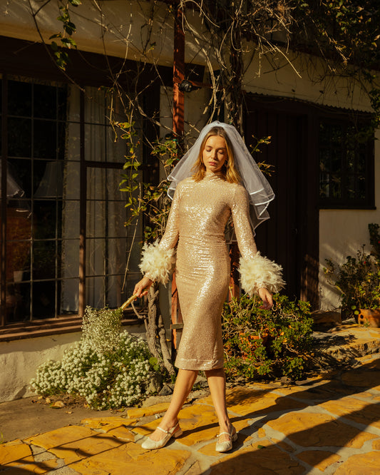 The sequined, bodycon design accentuates your curves, while the removable feather trim on the sleeves adds a touch of elegance.