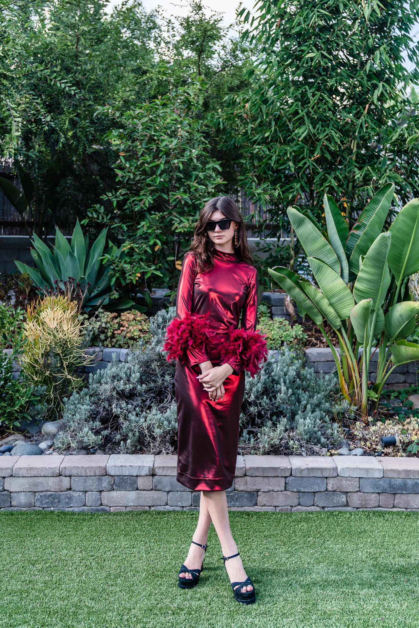 This cherry lamé, bodycon dress accentuates your curves, while the removable feather trim on the sleeves adds a touch of elegance.