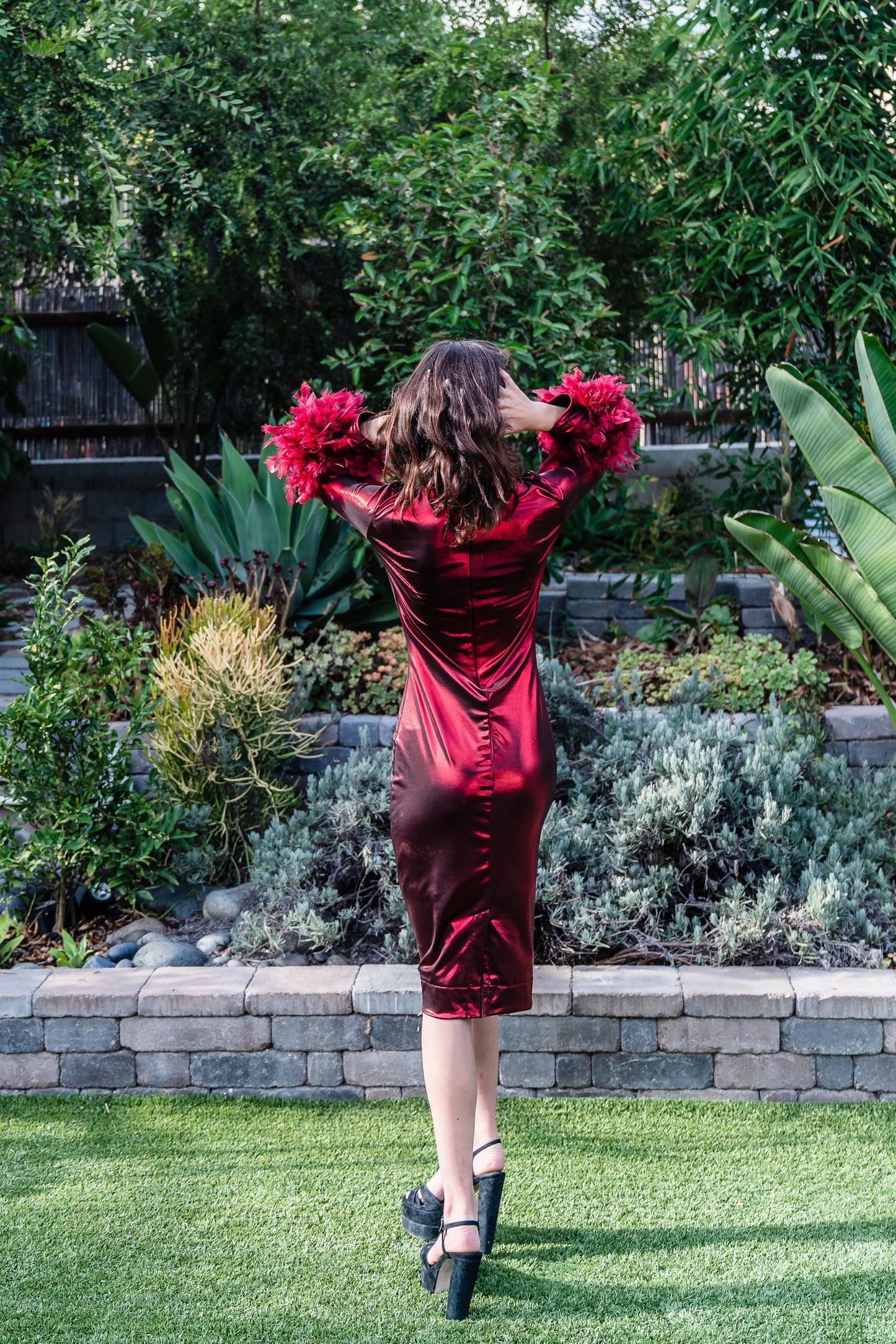 This cherry lamé, bodycon dress accentuates your curves, while the removable feather trim on the sleeves adds a touch of elegance.