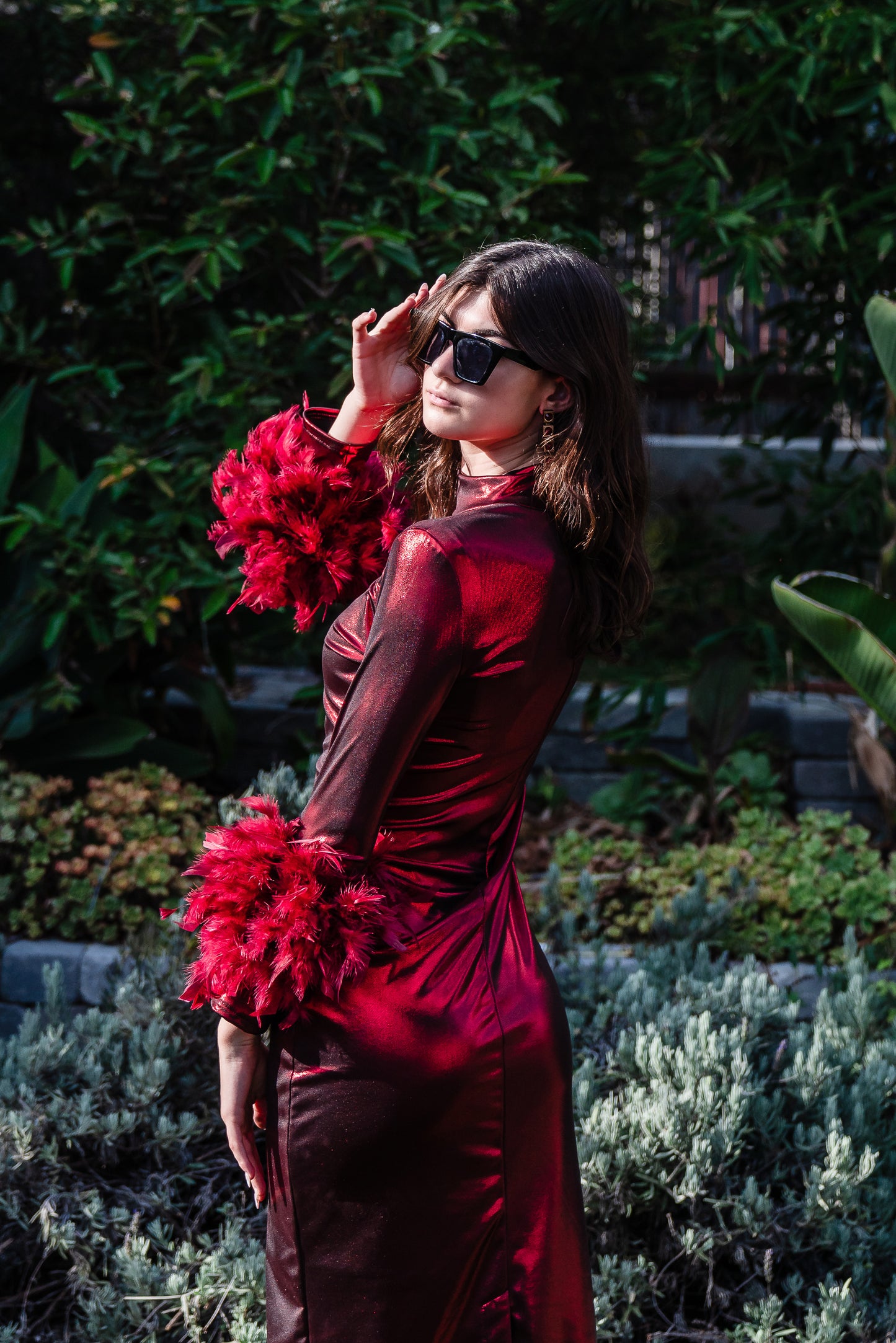 This cherry lamé, bodycon dress accentuates your curves, while the removable feather trim on the sleeves adds a touch of elegance.