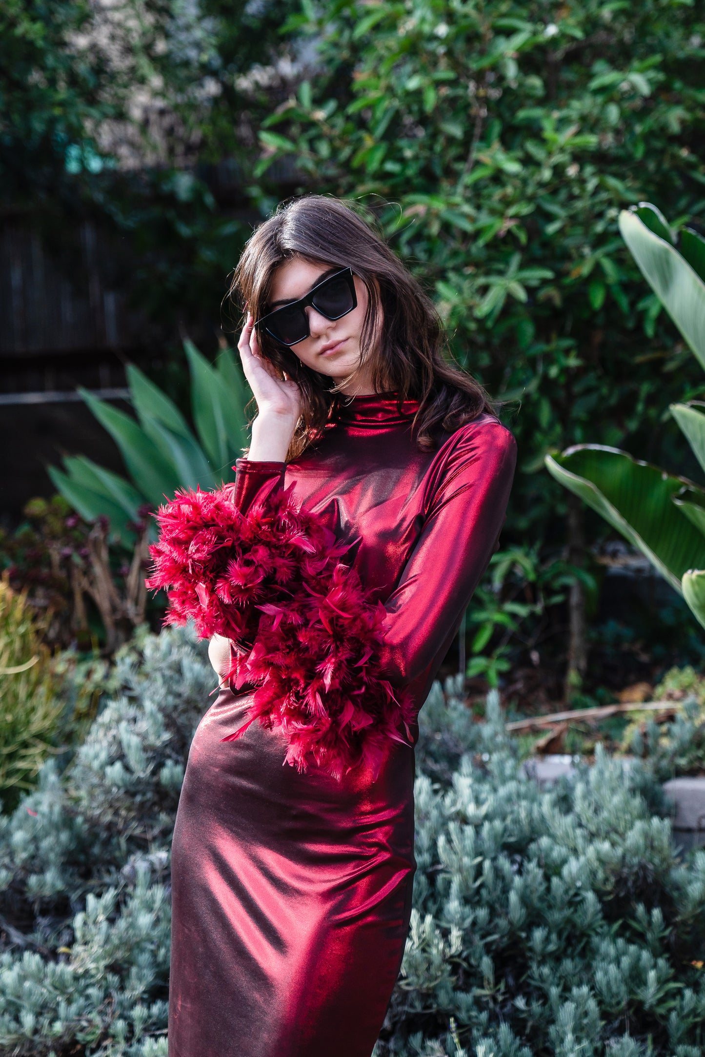 This cherry lamé, bodycon dress accentuates your curves, while the removable feather trim on the sleeves adds a touch of elegance.