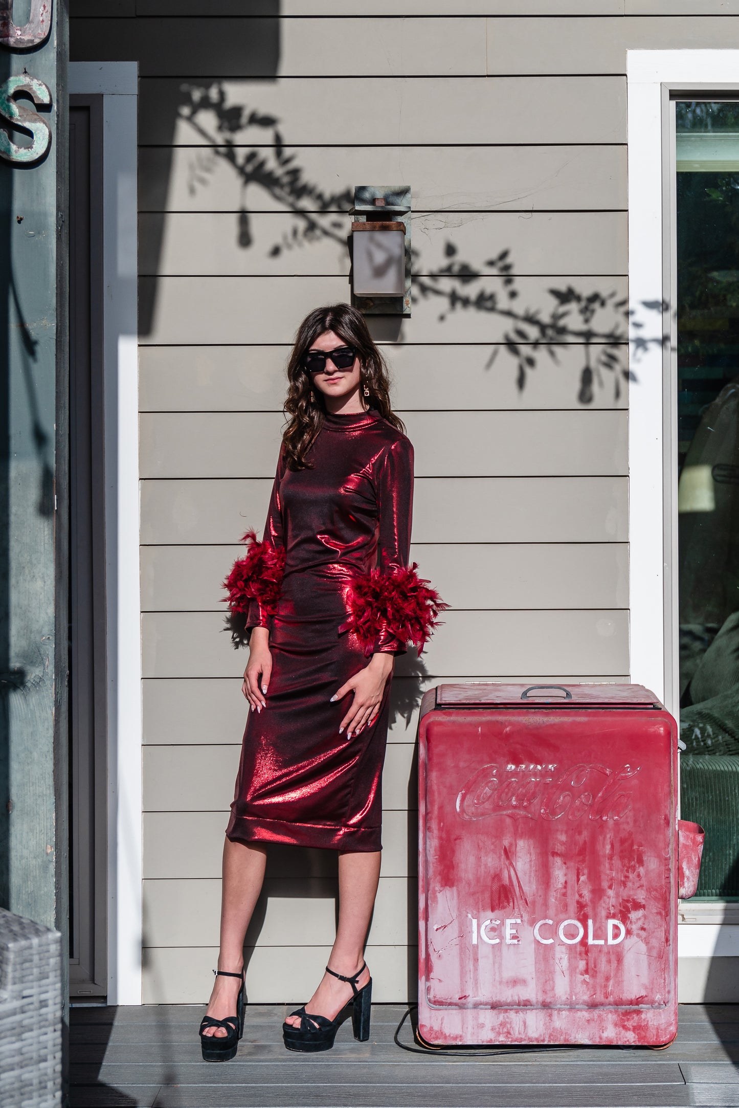 This cherry lamé, bodycon dress accentuates your curves, while the removable feather trim on the sleeves adds a touch of elegance.