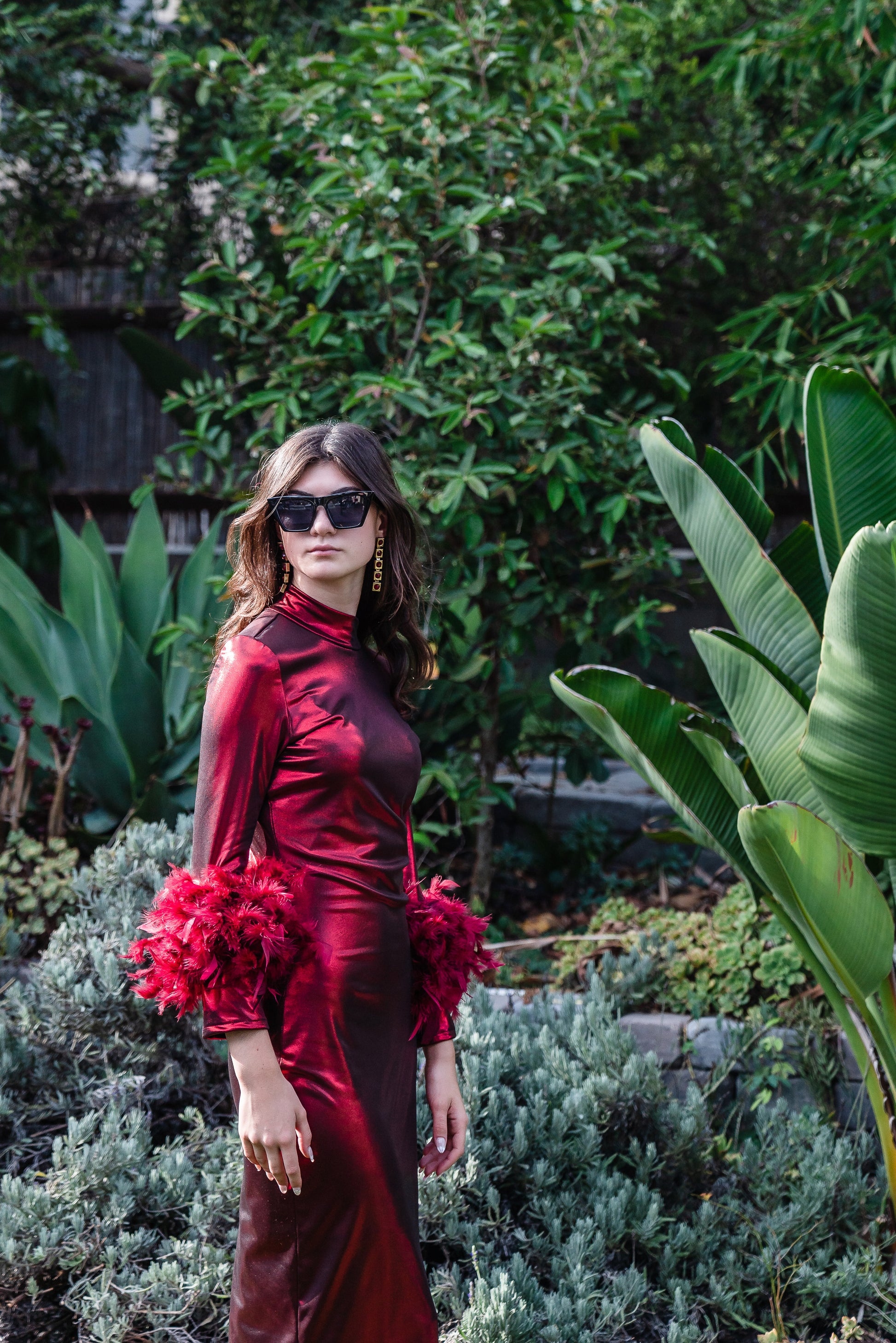 This cherry lamé, bodycon dress accentuates your curves, while the removable feather trim on the sleeves adds a touch of elegance.