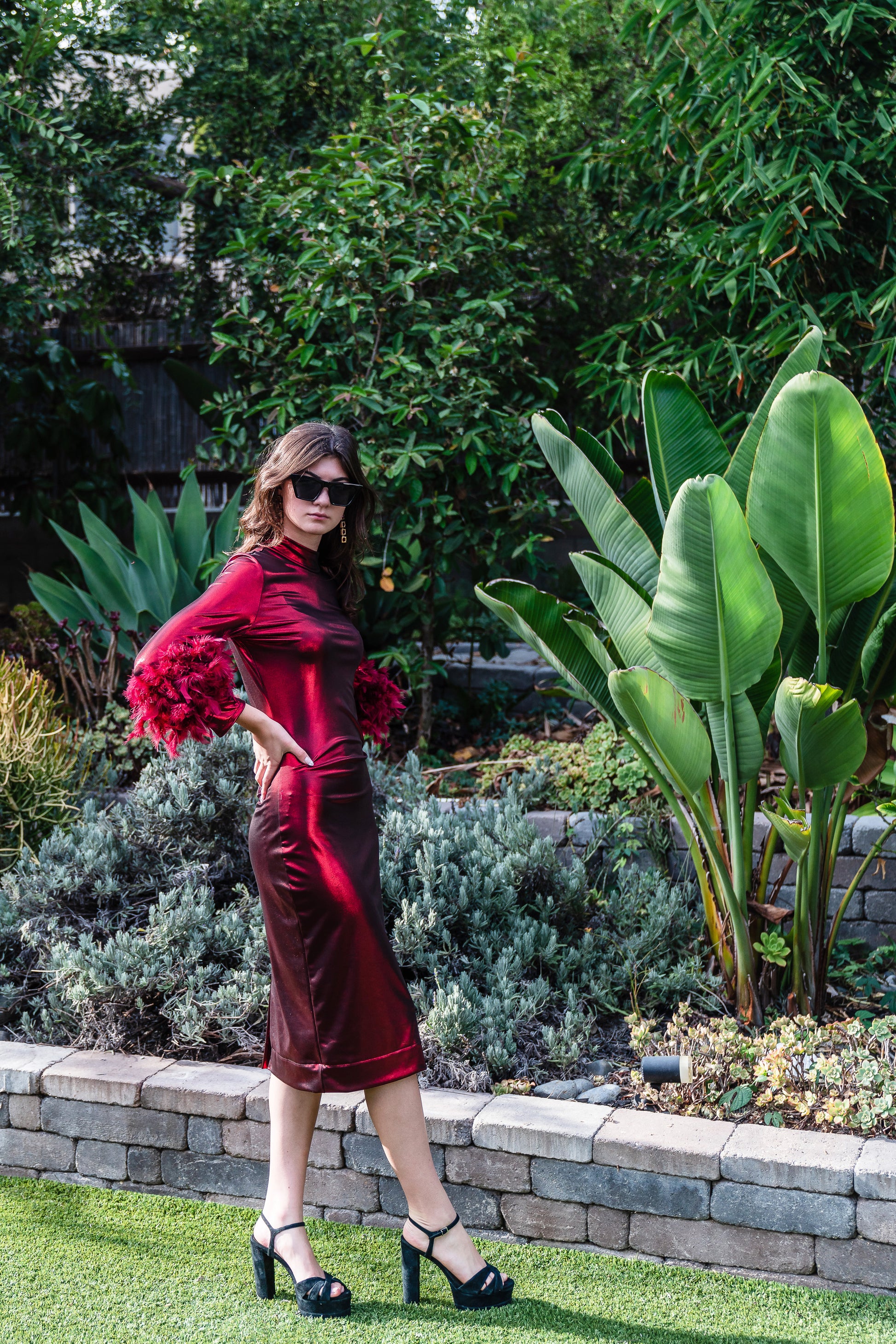 This cherry lamé, bodycon dress accentuates your curves, while the removable feather trim on the sleeves adds a touch of elegance.