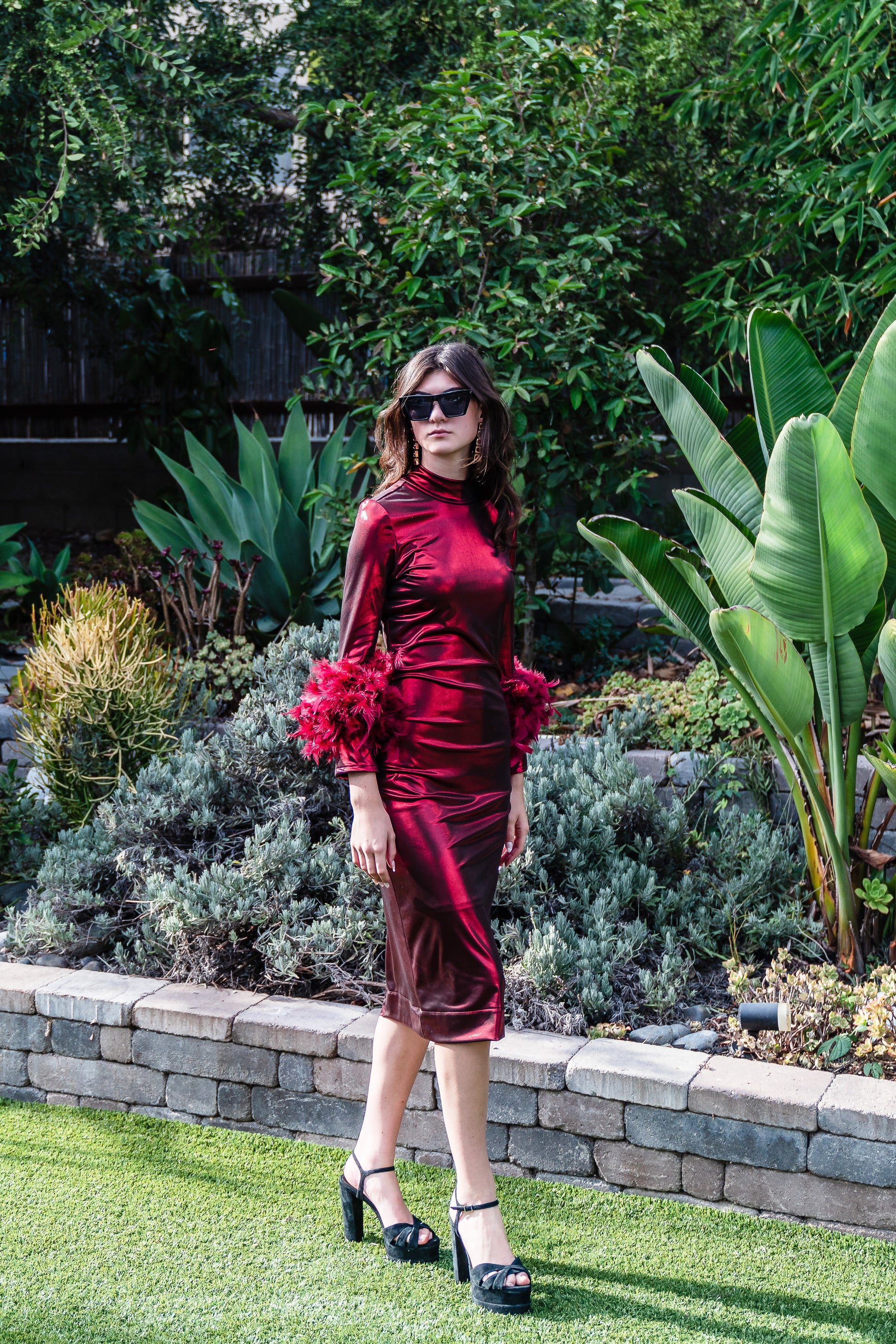 This cherry lamé, bodycon dress accentuates your curves, while the removable feather trim on the sleeves adds a touch of elegance.