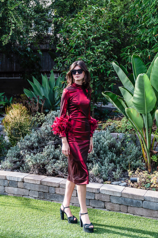 This cherry lamé, bodycon dress accentuates your curves, while the removable feather trim on the sleeves adds a touch of elegance.