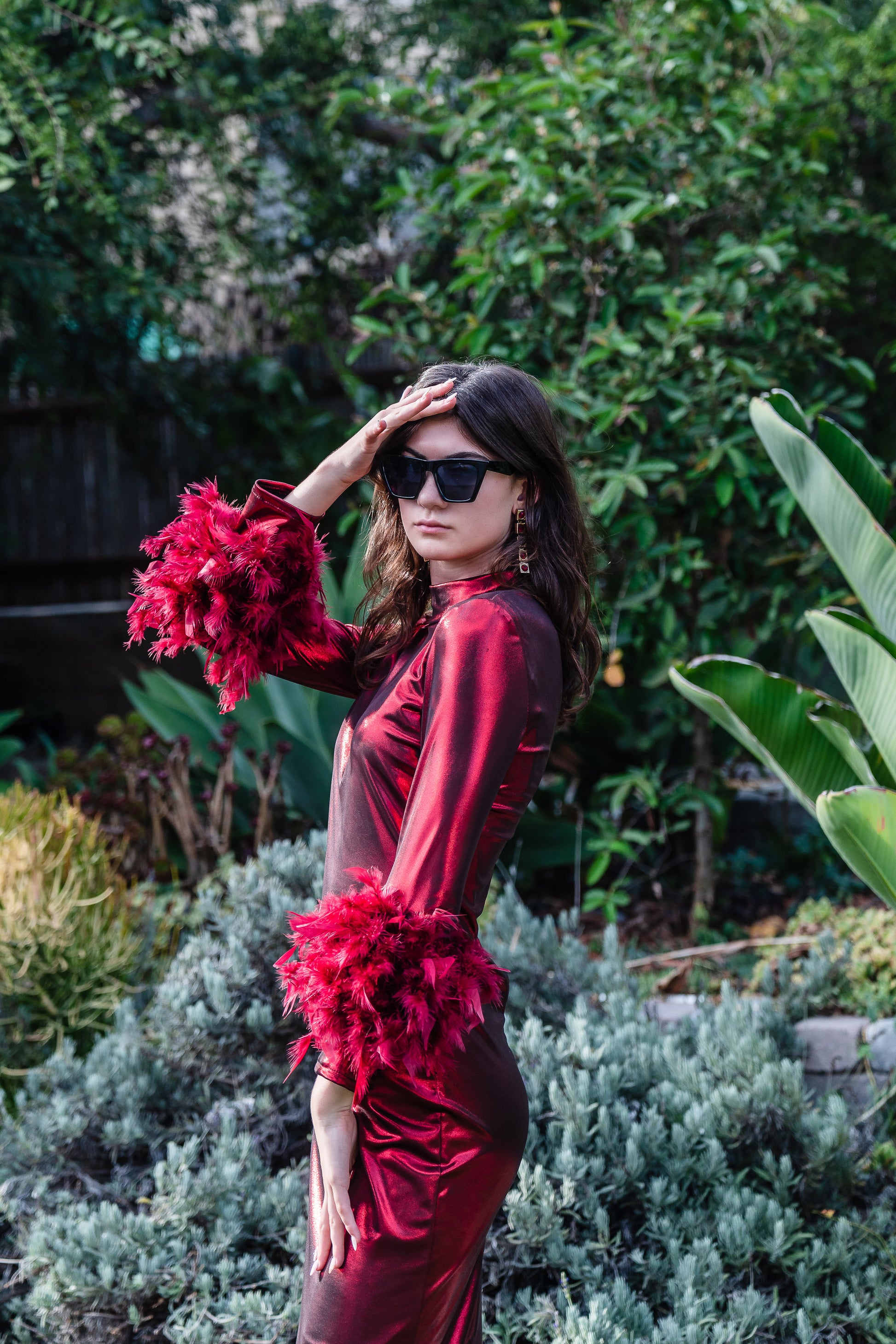 This cherry lamé, bodycon dress accentuates your curves, while the removable feather trim on the sleeves adds a touch of elegance.