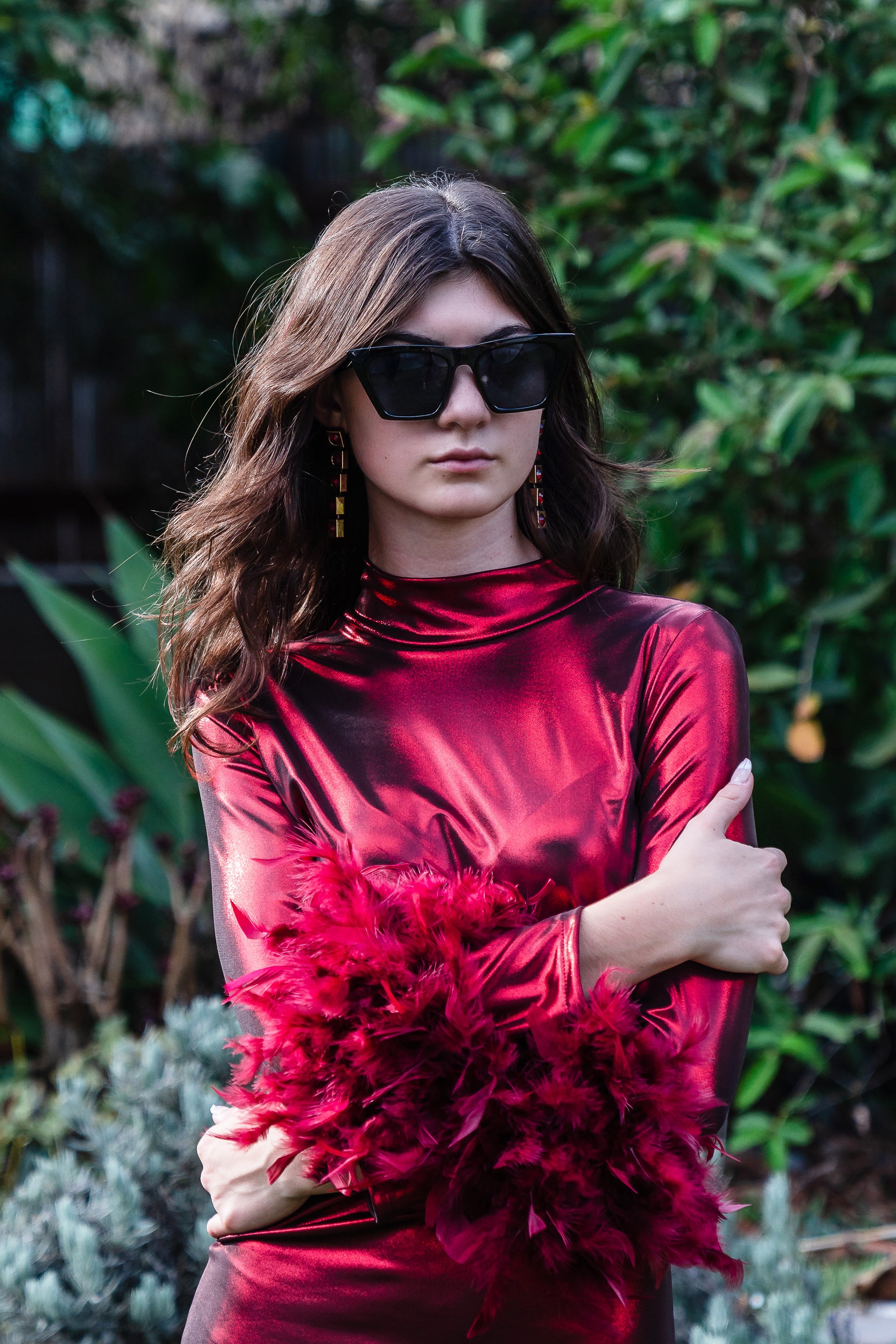 This cherry lamé, bodycon dress accentuates your curves, while the removable feather trim on the sleeves adds a touch of elegance.