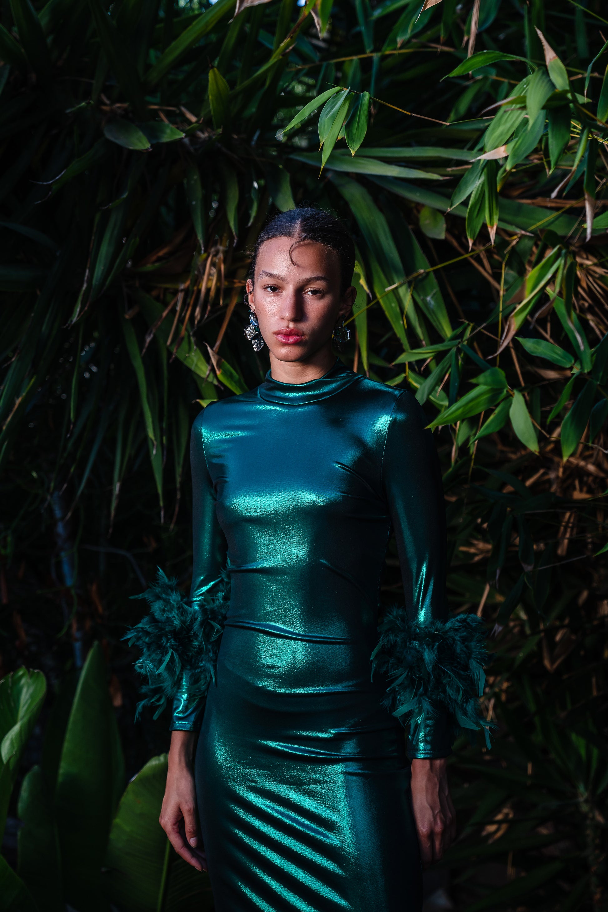 This emerald lamé, bodycon dress accentuates your curves, while the removable feather trim on the sleeves adds a touch of elegance.