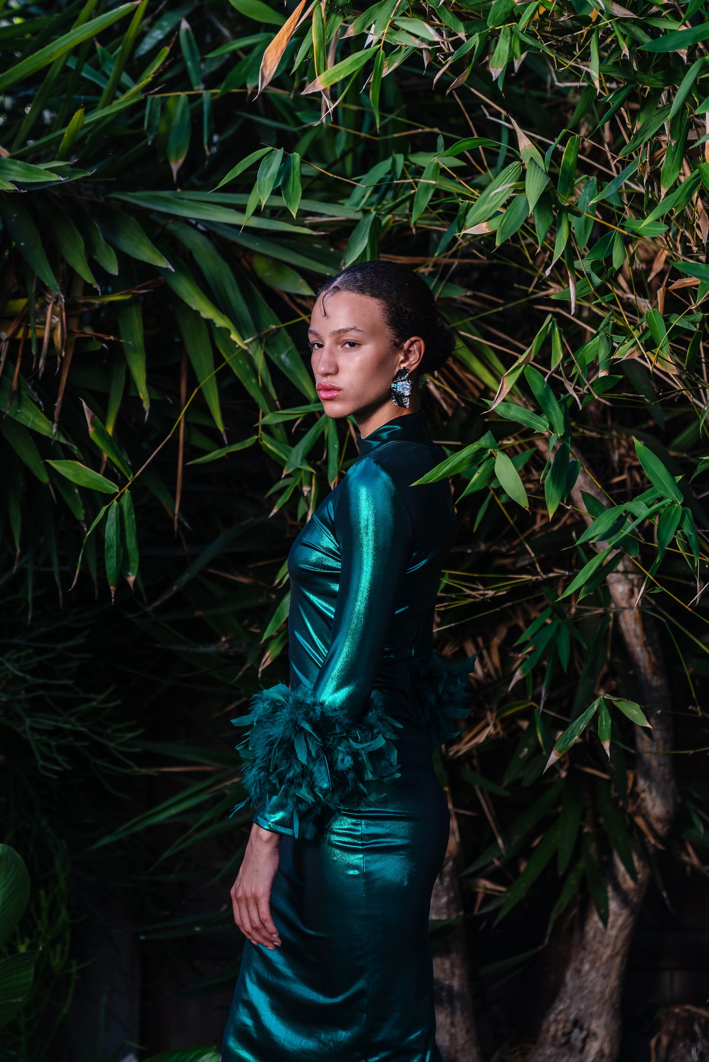 This emerald lamé, bodycon dress accentuates your curves, while the removable feather trim on the sleeves adds a touch of elegance.