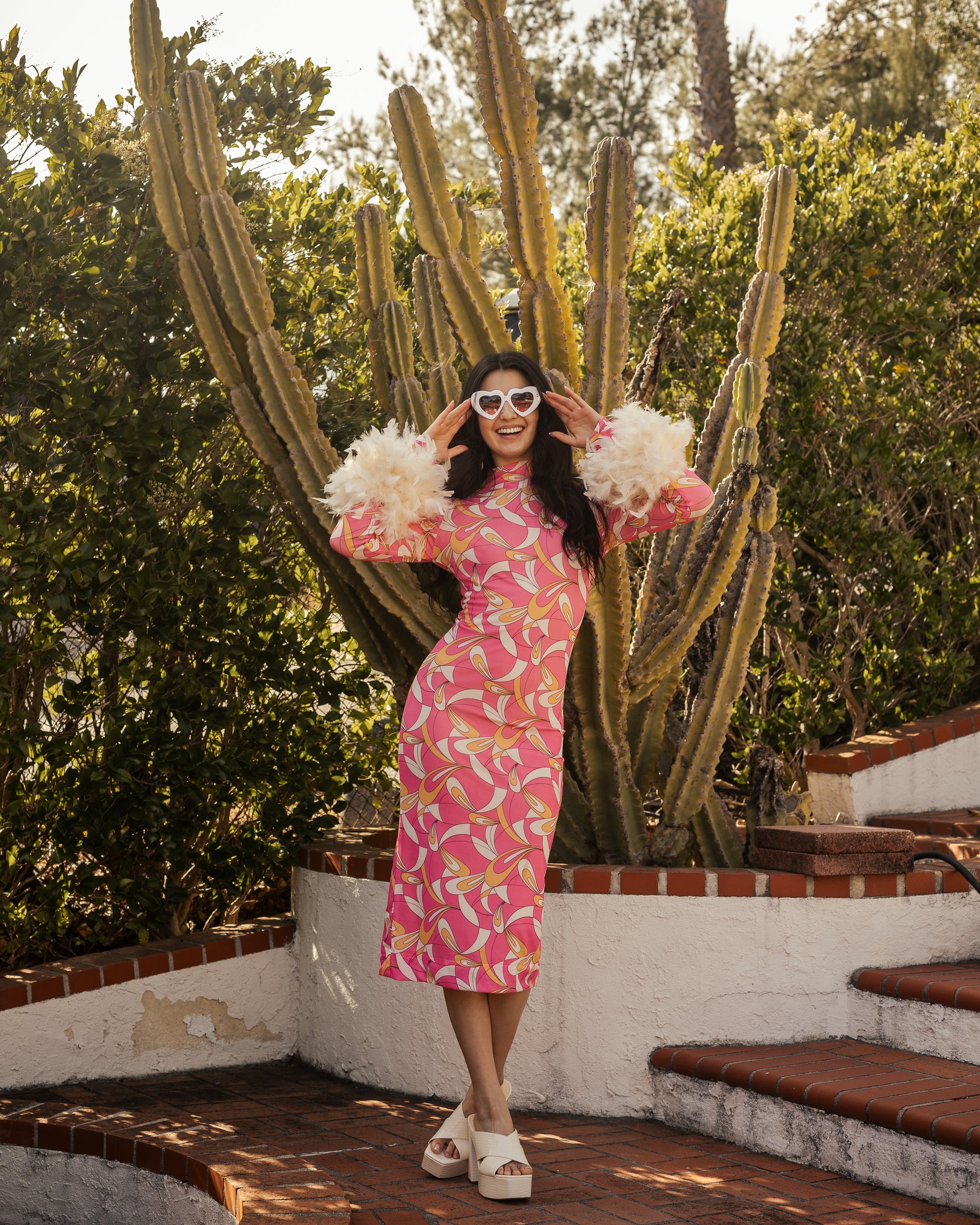 This pop-art bodycon design accentuates your curves, while the removable feather trim on the sleeves adds a touch of elegance.