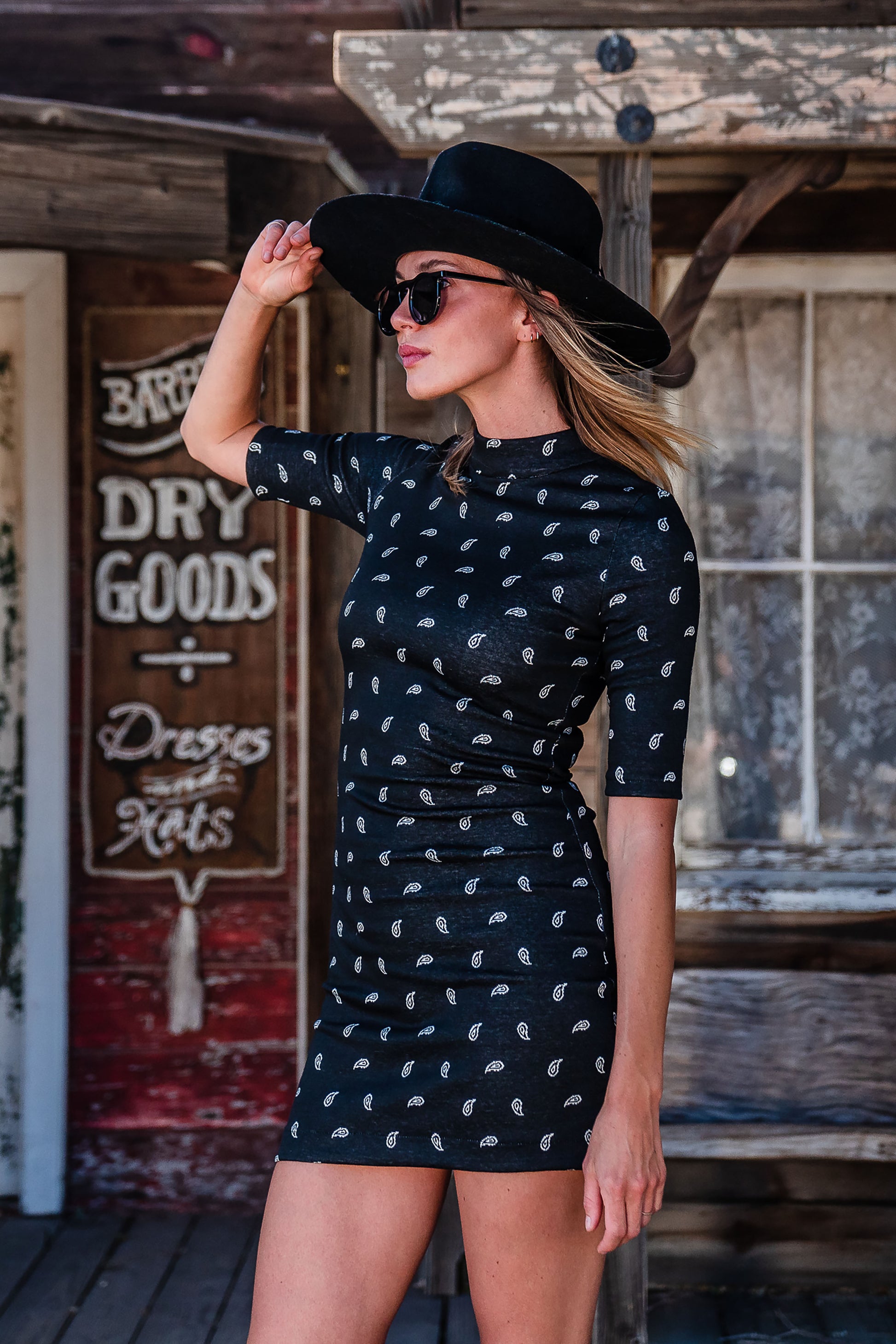 This Jennafer Grace mini dress features a black and white paisley print, elbow length short sleeves, a mock neck, and invisible zipper in back.