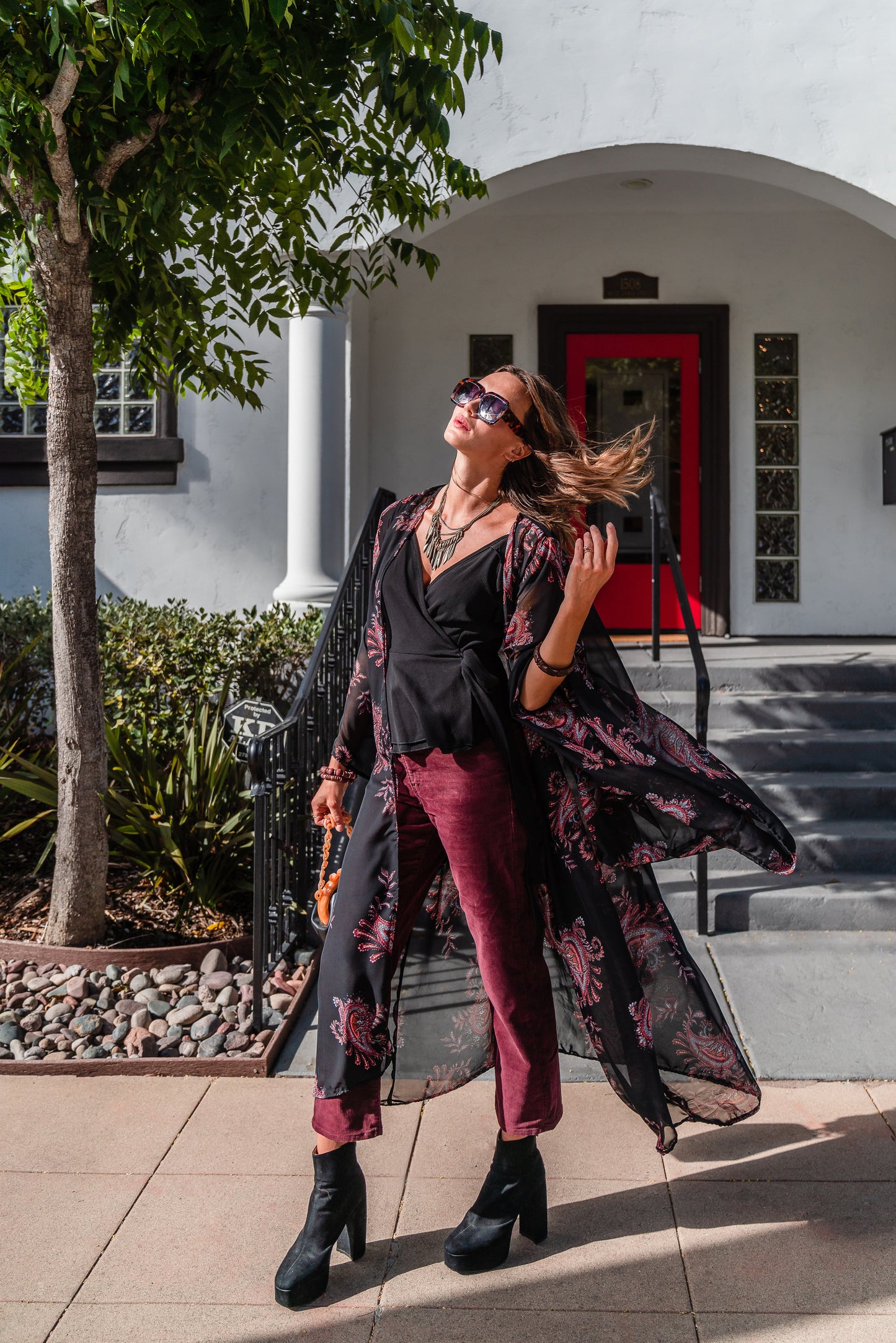 Introducing our Vera Paisley Kimono, with a black chiffon material is accented with a dark paisley pattern and pops of bordeaux, tan, and turquoise.