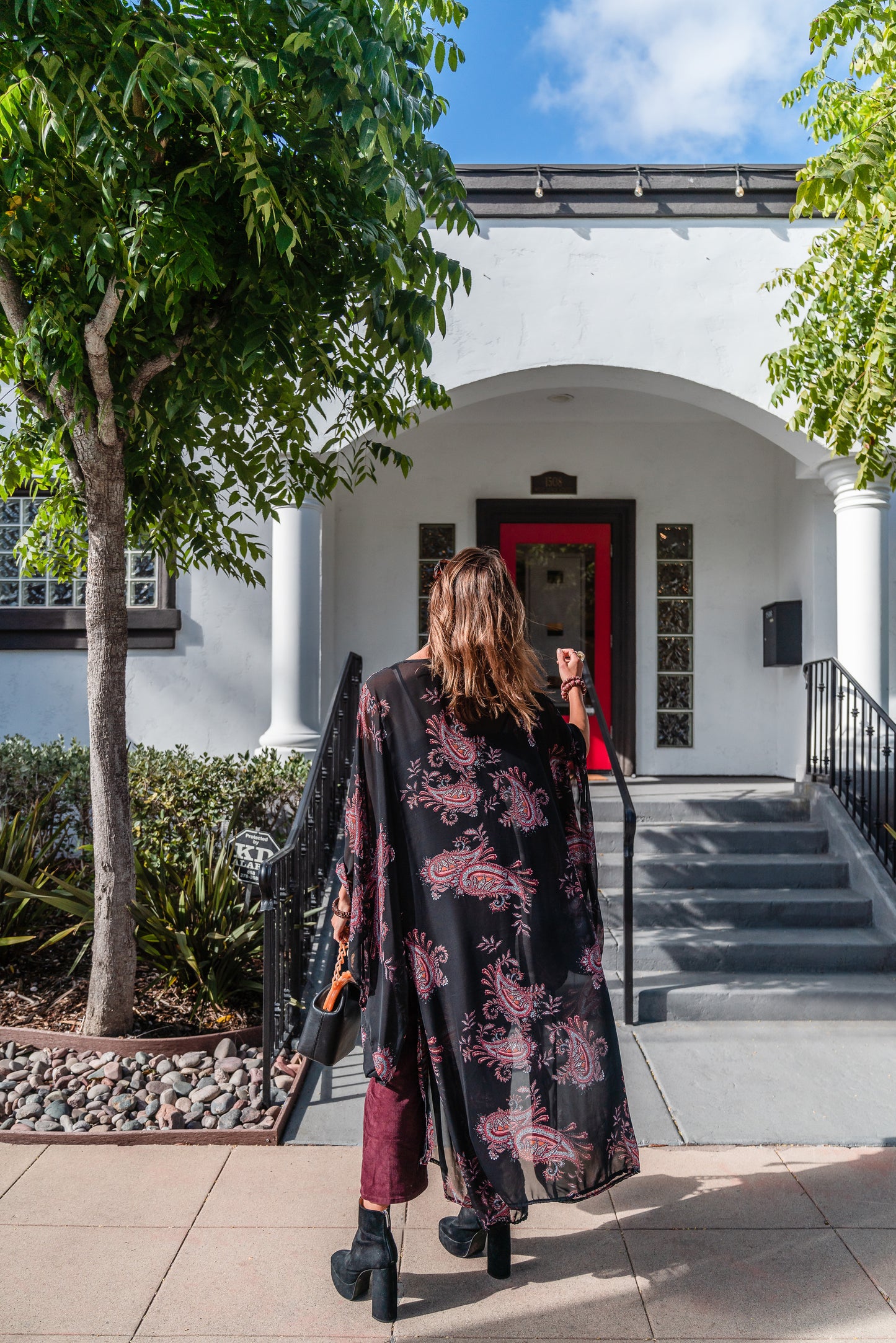 Introducing our Vera Paisley Kimono, with a black chiffon material is accented with a dark paisley pattern and pops of bordeaux, tan, and turquoise.