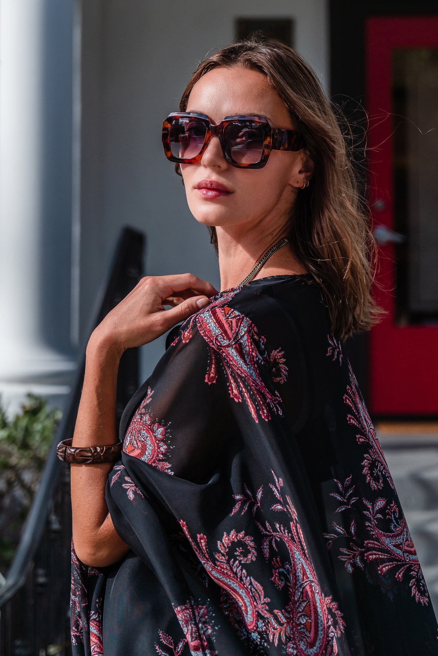 Introducing our Vera Paisley Kimono, with a black chiffon material is accented with a dark paisley pattern and pops of bordeaux, tan, and turquoise.