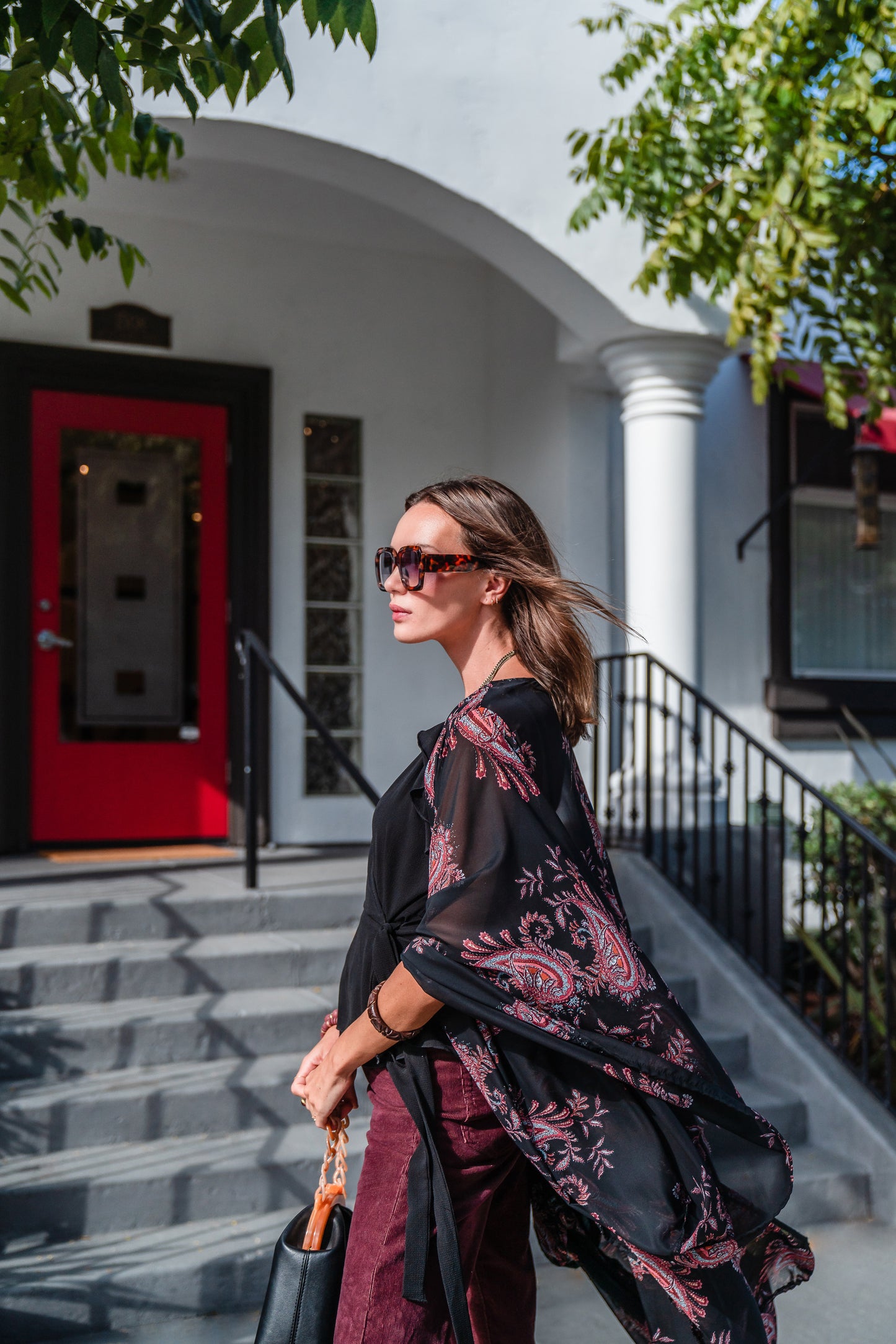 Introducing our Vera Paisley Kimono, with a black chiffon material is accented with a dark paisley pattern and pops of bordeaux, tan, and turquoise.