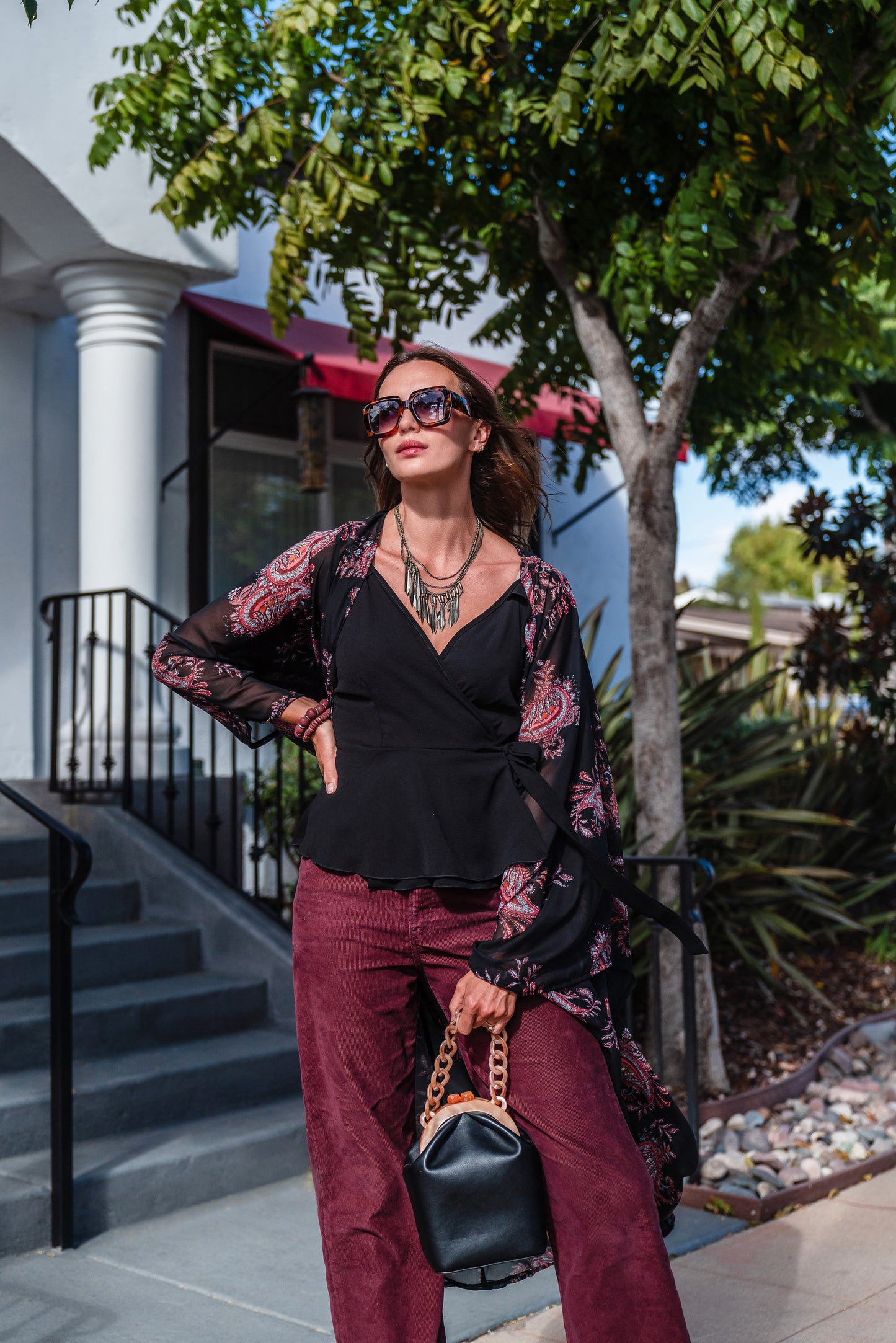 Introducing our Vera Paisley Kimono, with a black chiffon material is accented with a dark paisley pattern and pops of bordeaux, tan, and turquoise.