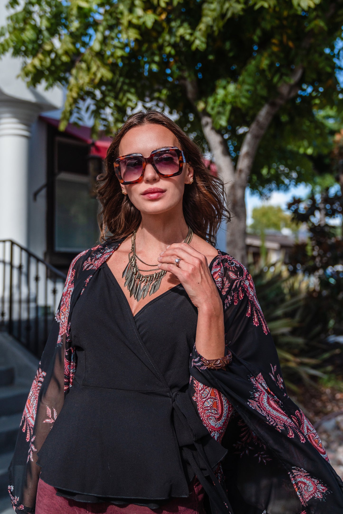 Introducing our Vera Paisley Kimono, with a black chiffon material is accented with a dark paisley pattern and pops of bordeaux, tan, and turquoise.
