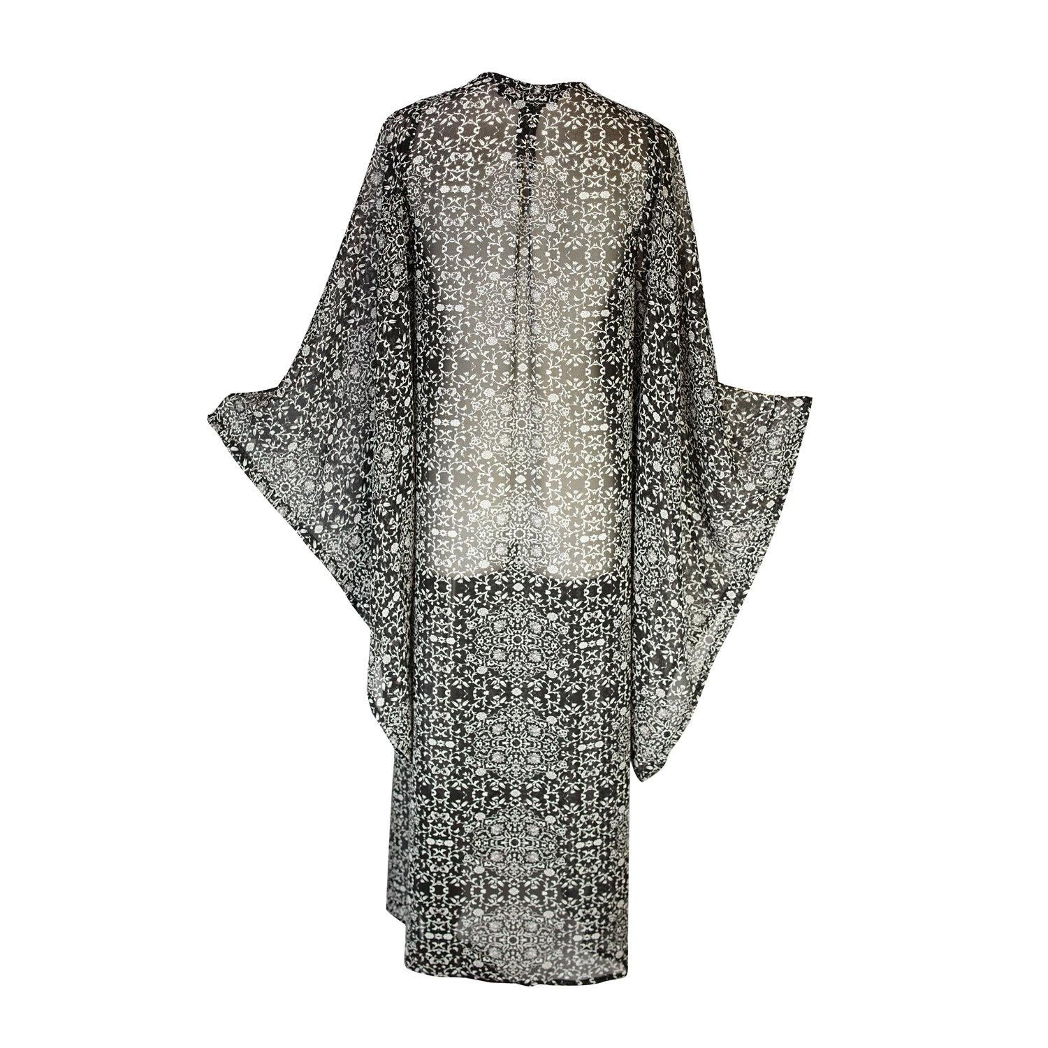 Long sleeve kimono with ankle length hem is made from a soft semi-sheer rayon chiffon. Featuring a black and white victorian floral pattern. It also features pockets, deep v-neck when tied shut, and a matching waist tie-you can style this piece in at least 10 ways.