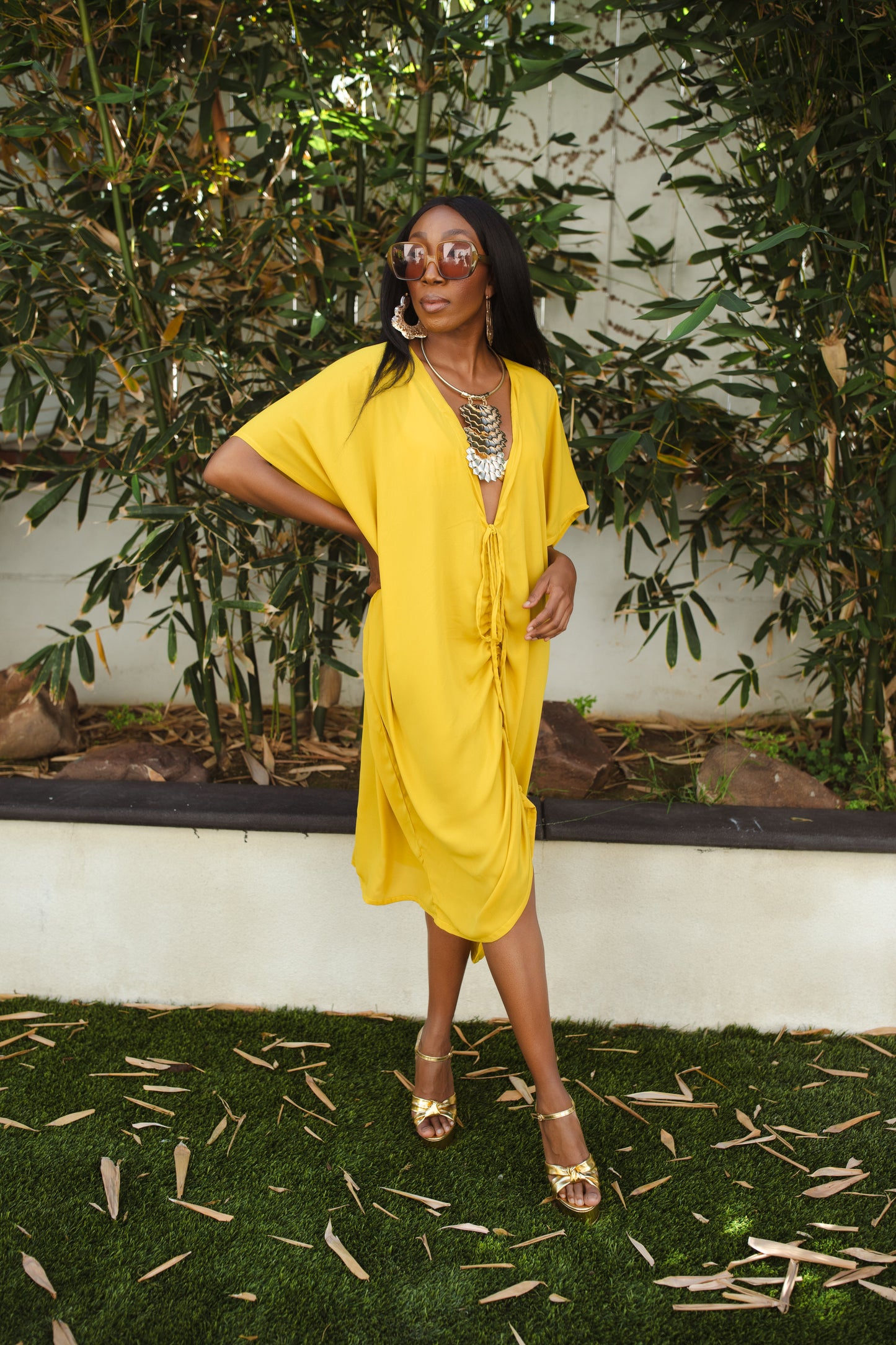 Vibrant yellow caftan. This piece features a deep v-neck, batwing sleeve, a center drawstring for ruche styling, and ankle length hem. Retro bohemian aesthetic.