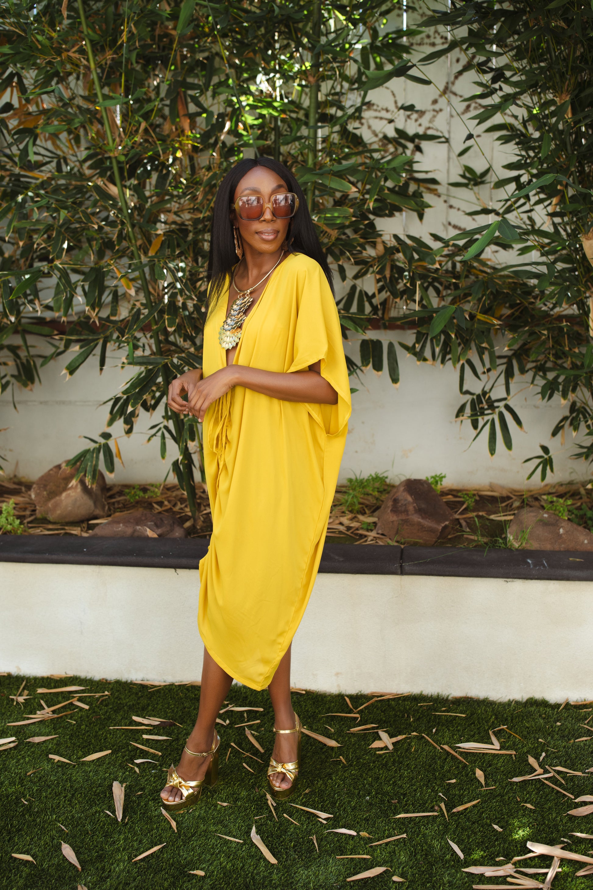 Vibrant yellow caftan. This piece features a deep v-neck, batwing sleeve, a center drawstring for ruche styling, and ankle length hem. Retro bohemian aesthetic.