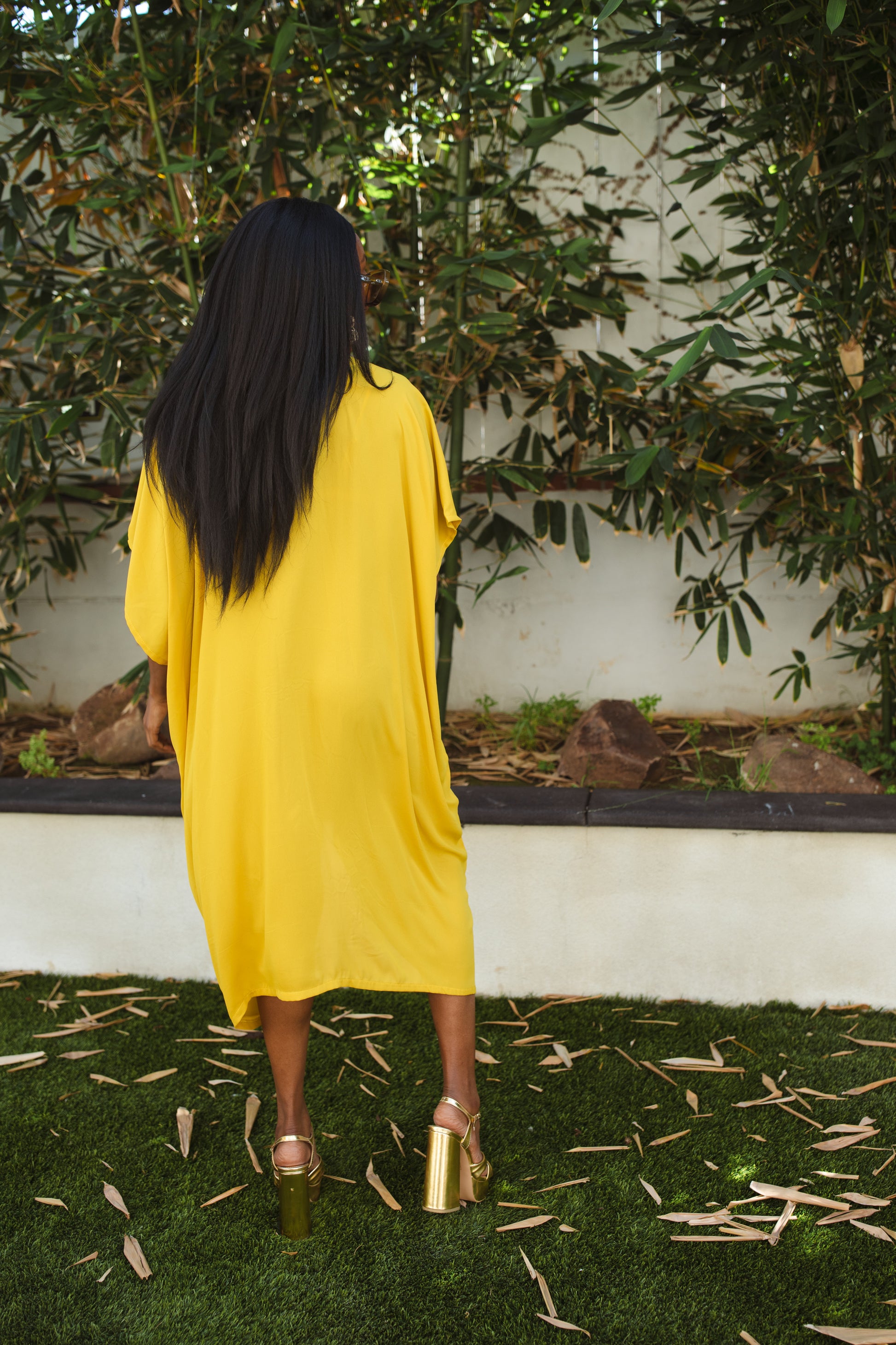 Vibrant yellow caftan. This piece features a deep v-neck, batwing sleeve, a center drawstring for ruche styling, and ankle length hem. Retro bohemian aesthetic.