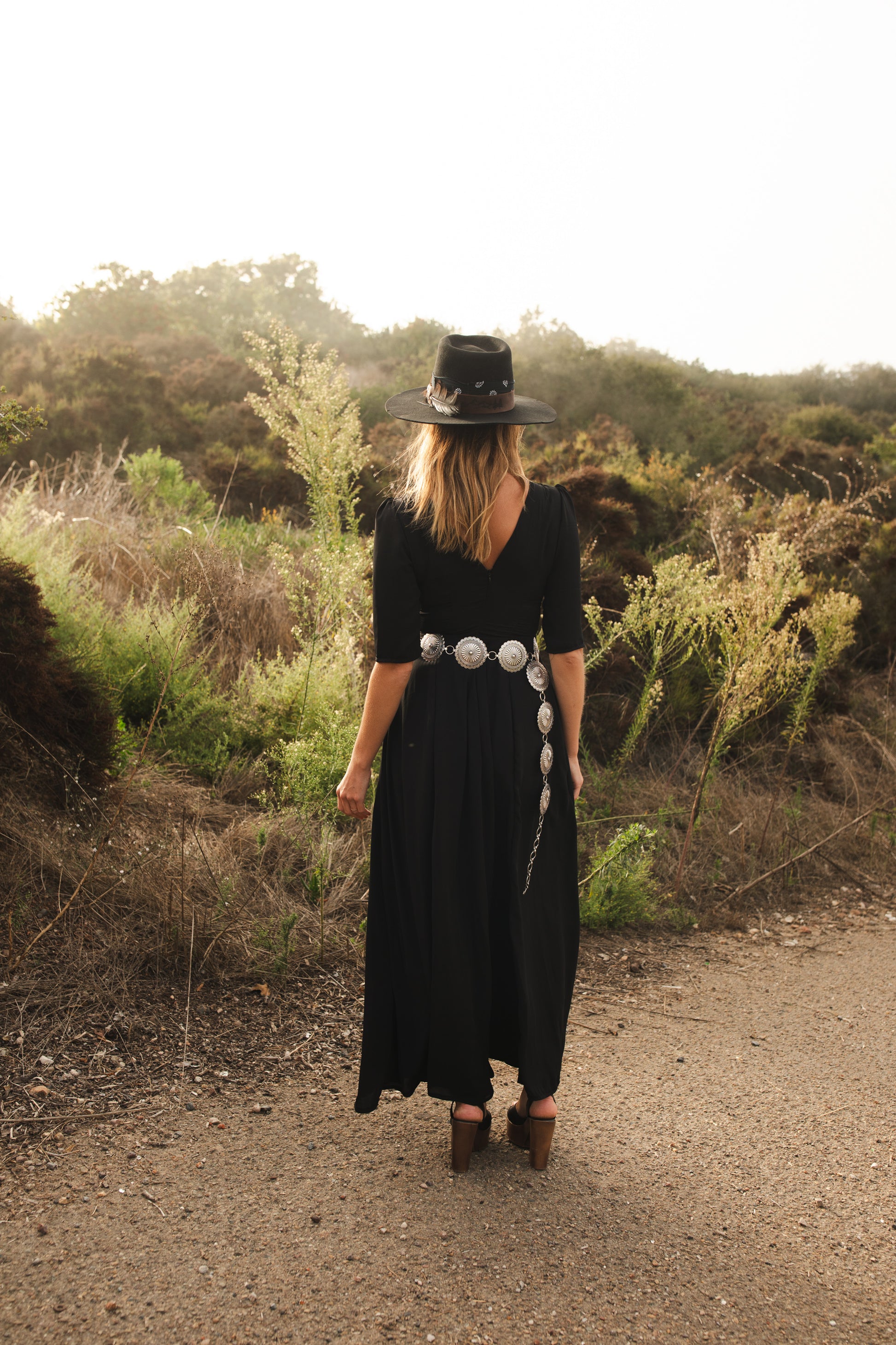 Jennafer Grace solid black maxi dress features princess seamed skirts and pockets. The dress has an invisible zipper and high/low neck options you can wear it multiple ways. Fitted torso with elbow length sleeves and ankle hem. 