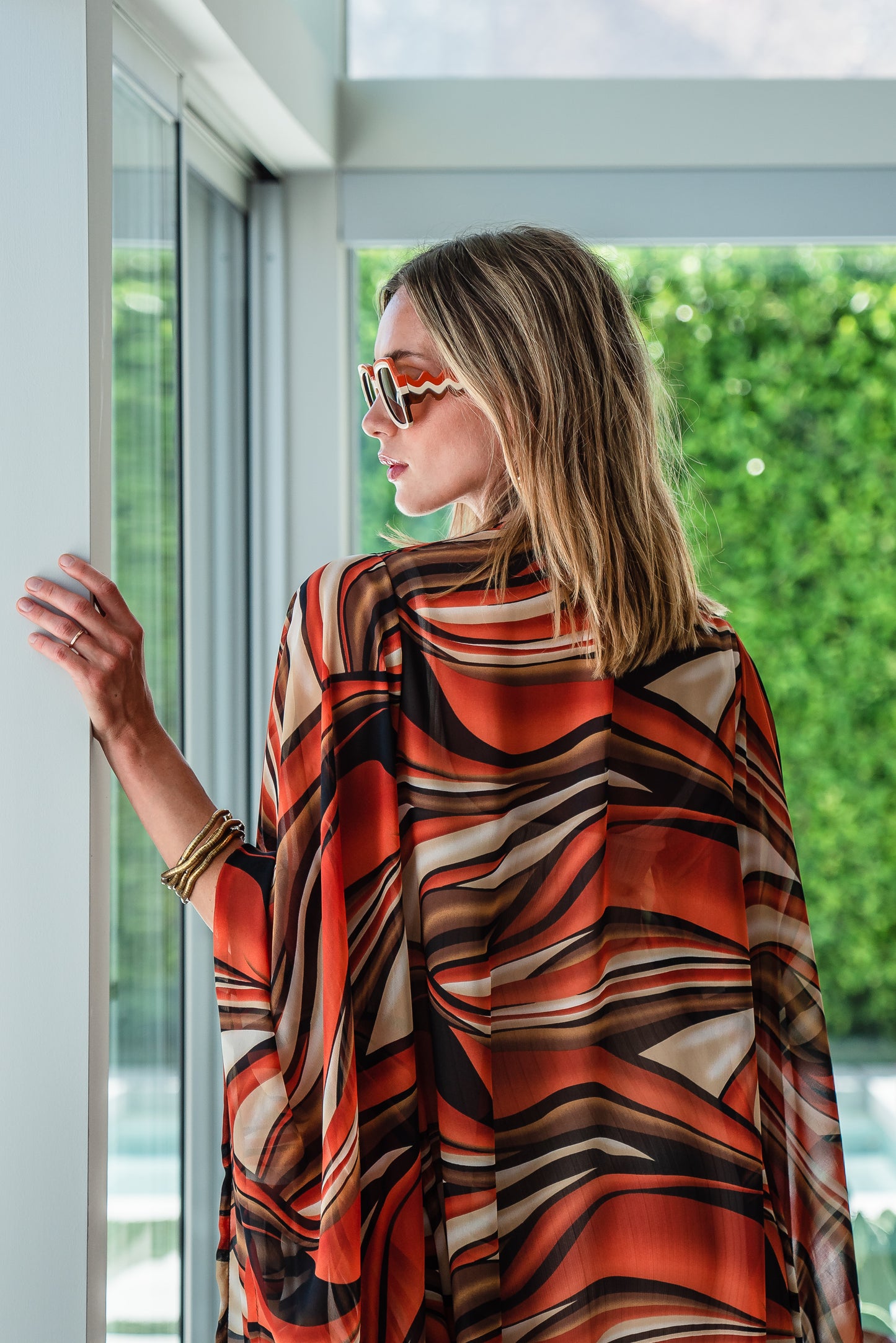 Inspired by the River Styx, the Styx Kimono is a fiery and versatile addition to your wardrobe. Made from chiffon, its abstract geometric design in shades of orange, red, and brown adds a touch of elegance to any outfit.