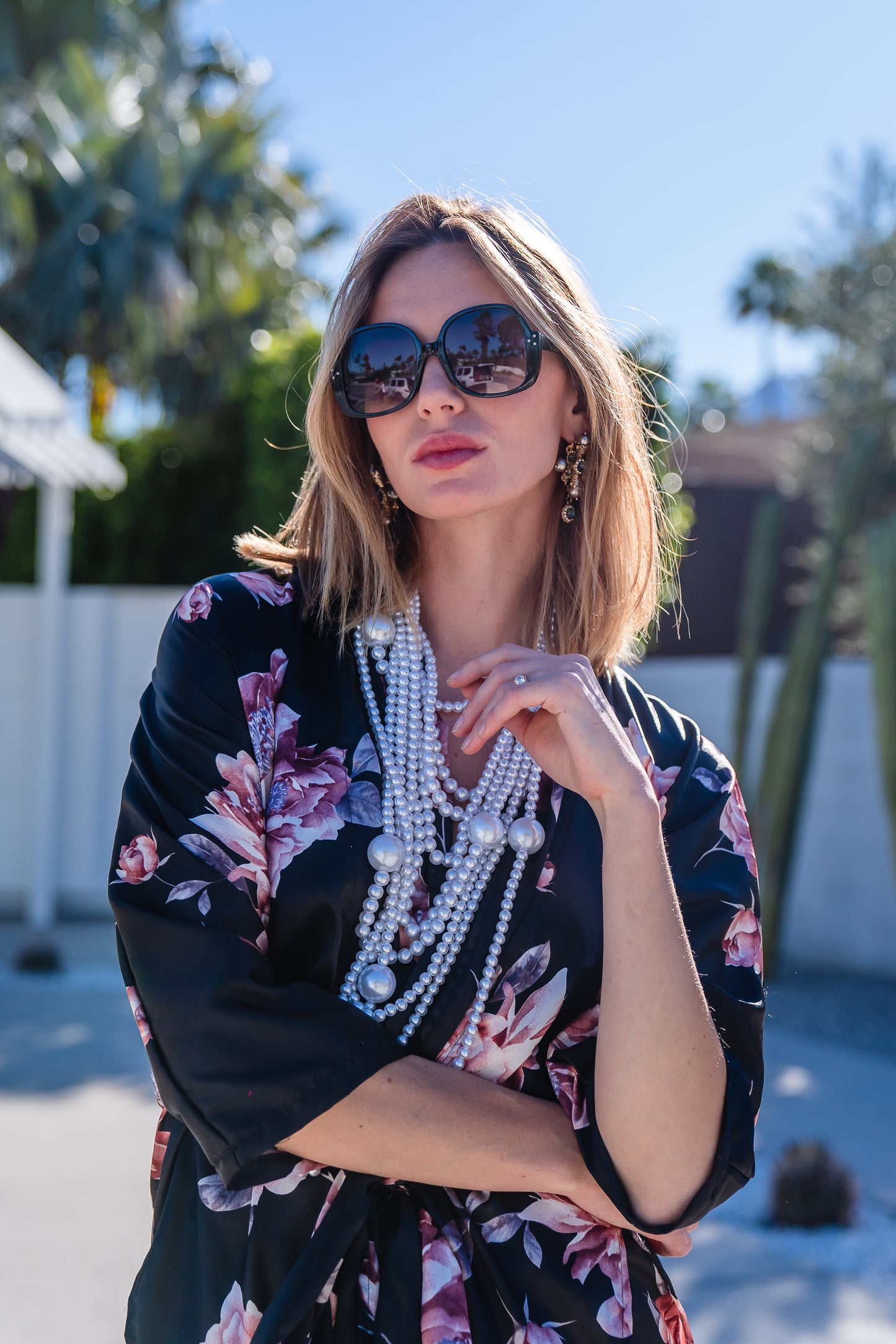 Loungewear set in dark floral pattern. A black background with light pink flowers, this set comes with a wrap dolman jacket.  Sleeves have a forearm hem, and it can be worn as an open jacket or wrap with matching tie belt. The belt features fringe tassels. The matching pants have pockets and an ankle length hem. 