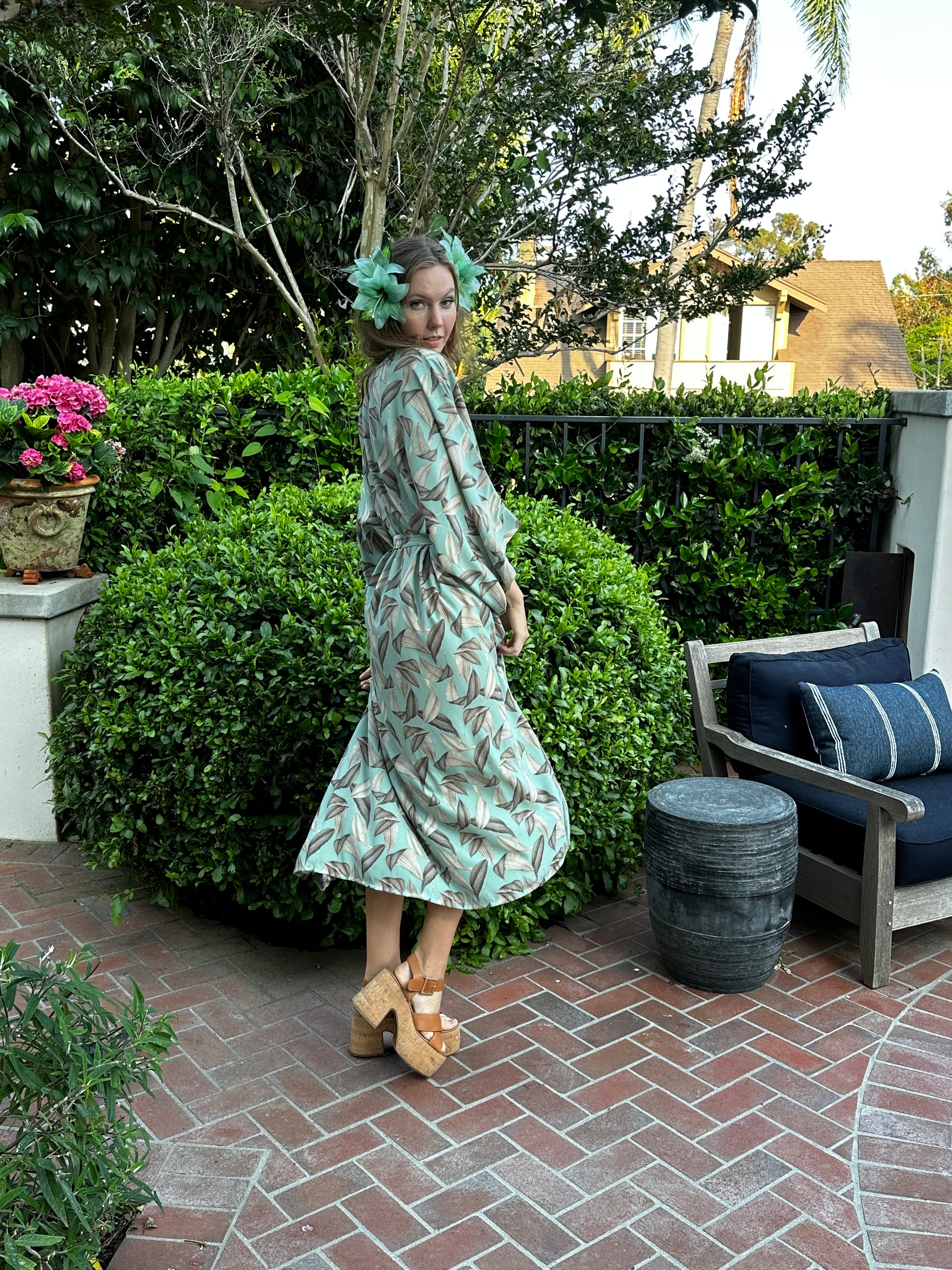 The Menta Dulce Belted Disco caftan dress featuring a mint colored palm print, batwing sleeves, boat neck, ankle hem, and optional belt to promote a flattering silhouette.