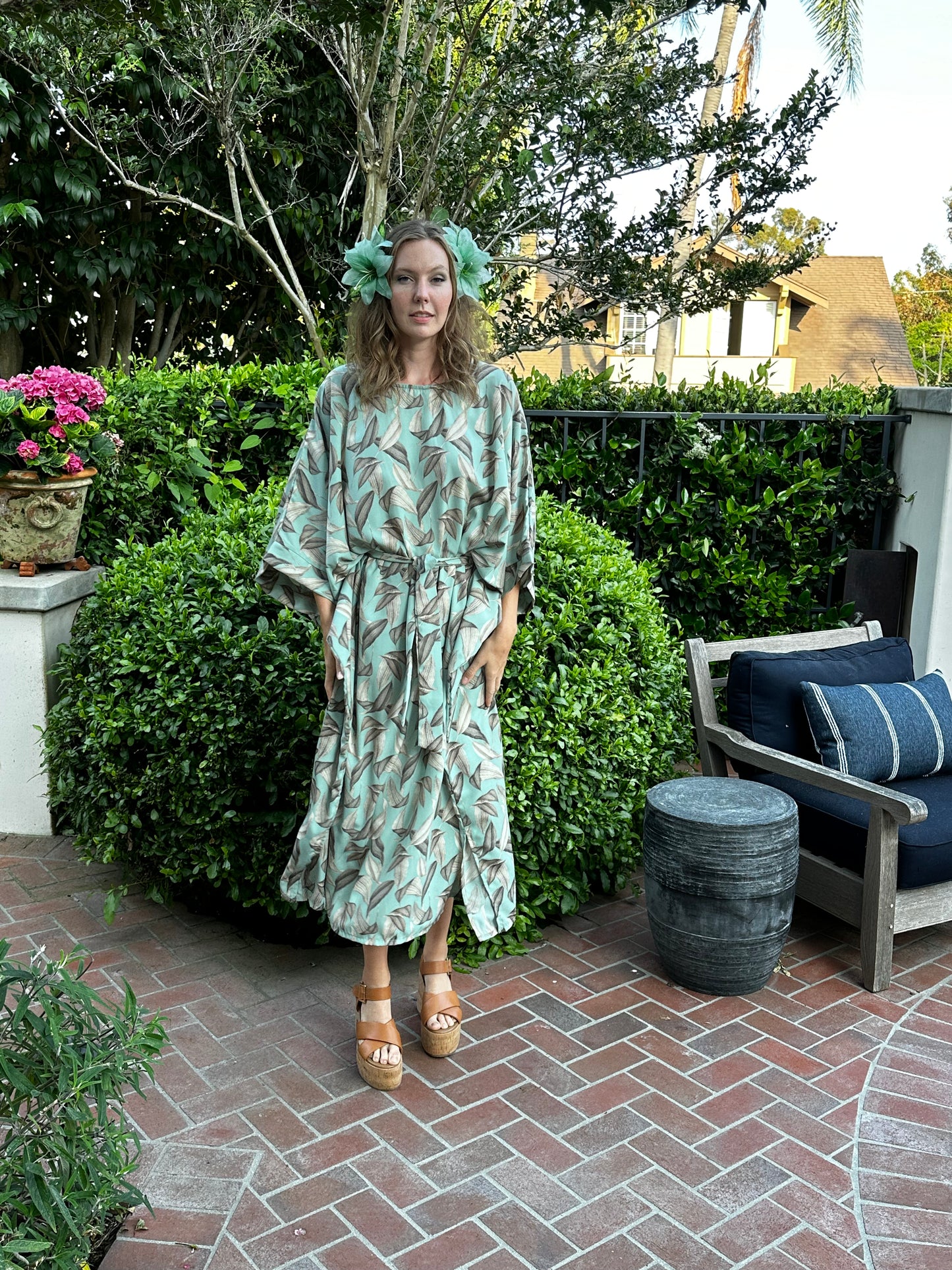 The Menta Dulce Belted Disco caftan dress featuring a mint colored palm print, batwing sleeves, boat neck, ankle hem, and optional belt to promote a flattering silhouette.