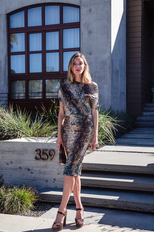 Snakeskin printed dress. Made from stretchy jersey fabric this dress features a fitted pencil skirt fit with light ruching at the hip. Mid-length angled sleeves can arrange the neckline to reveal a peek of the shoulder. Hemline below knee.