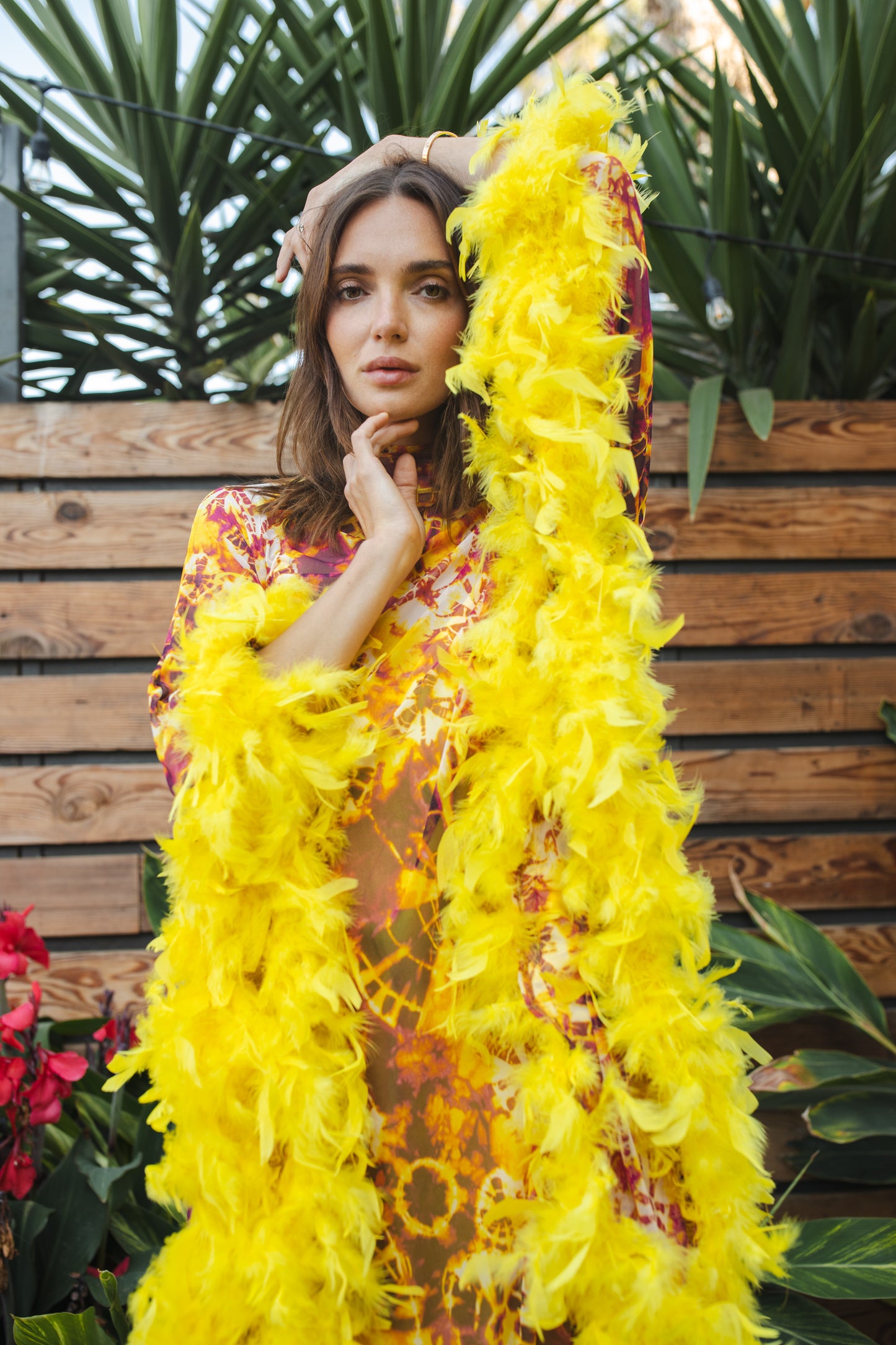 The Intra Dimensiona Mockneck Feather Caftan with slip. A vibrant, fiery abstract print featuring reds and oranges and yellows printed on a semi-sheer, super soft mesh with canary yellow feather border along sleeves and hem. A bohemian dress inspired by Old Hollywood and Palm Springs.