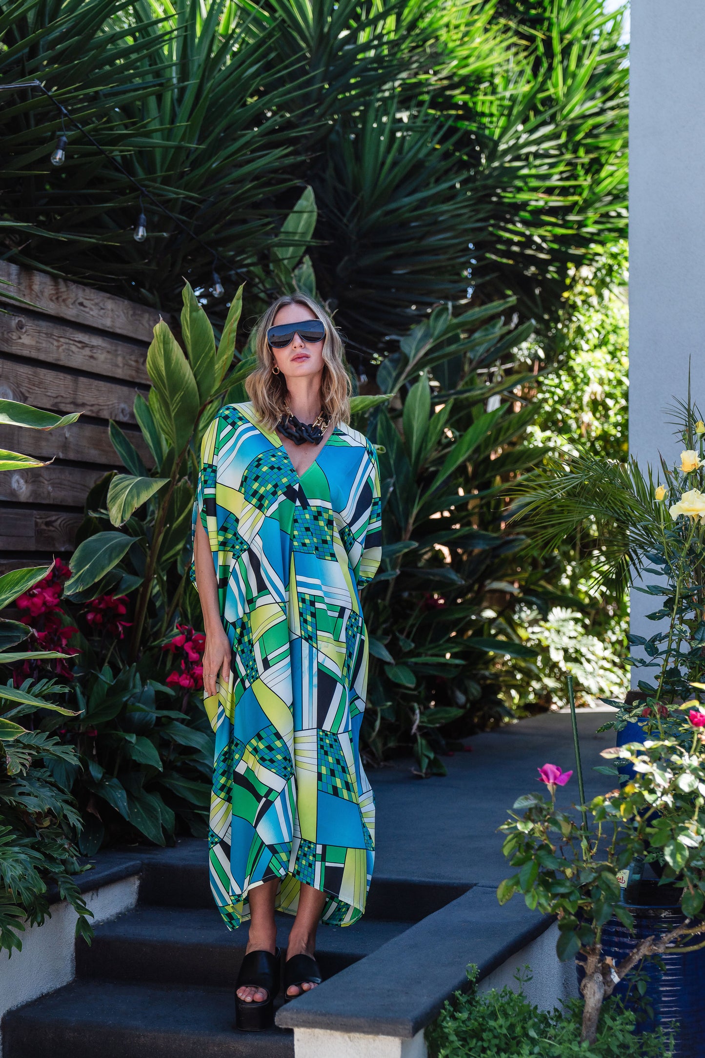 Jennafer Grace caftan in Pucci inspired mosaic print. Featuring an array of blue and green colors, this caftan features a deep v-neck, batwing sleeves, and ankle length hem.  