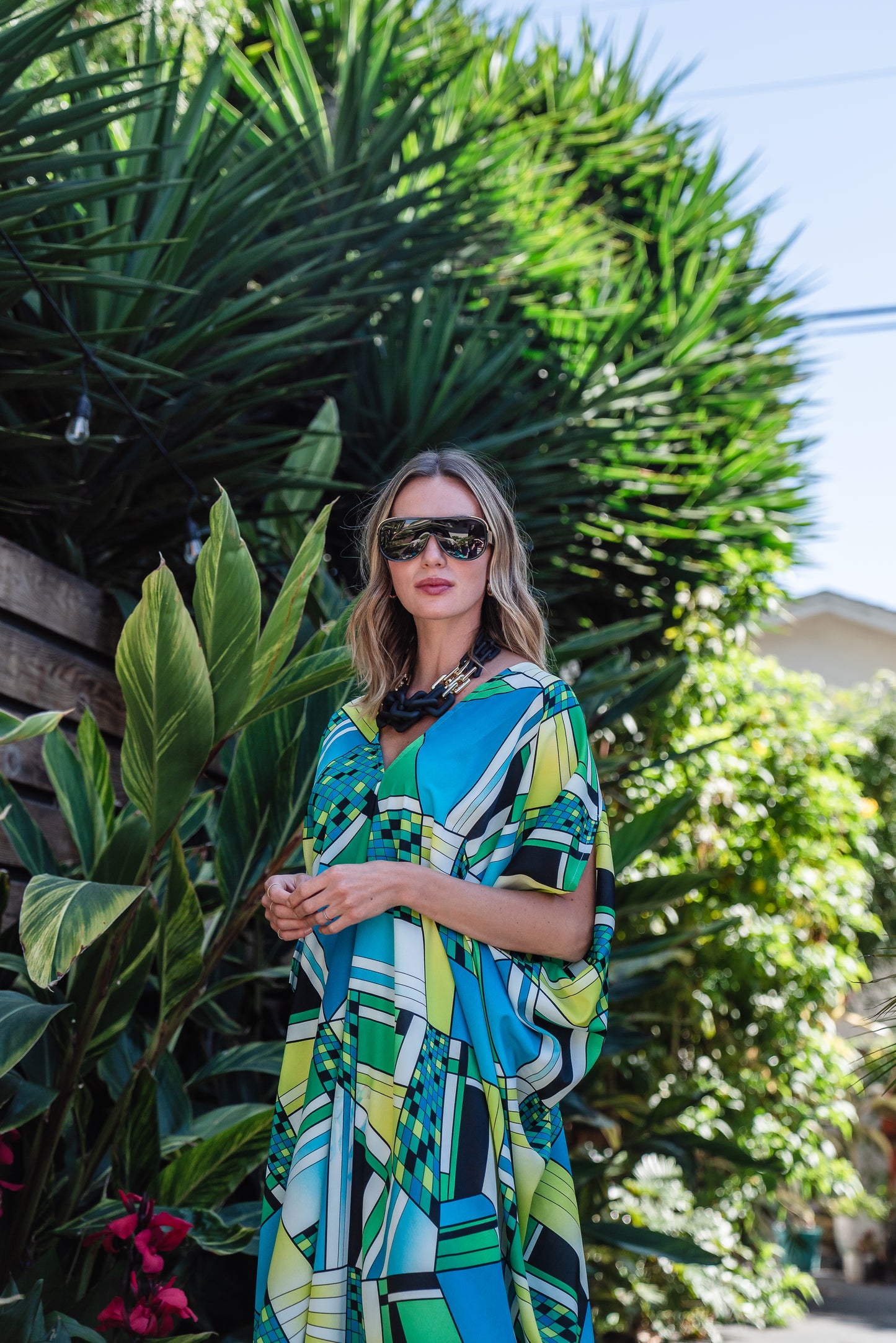 Jennafer Grace caftan in Pucci inspired mosaic print. Featuring an array of blue and green colors, this caftan features a deep v-neck, batwing sleeves, and ankle length hem.  