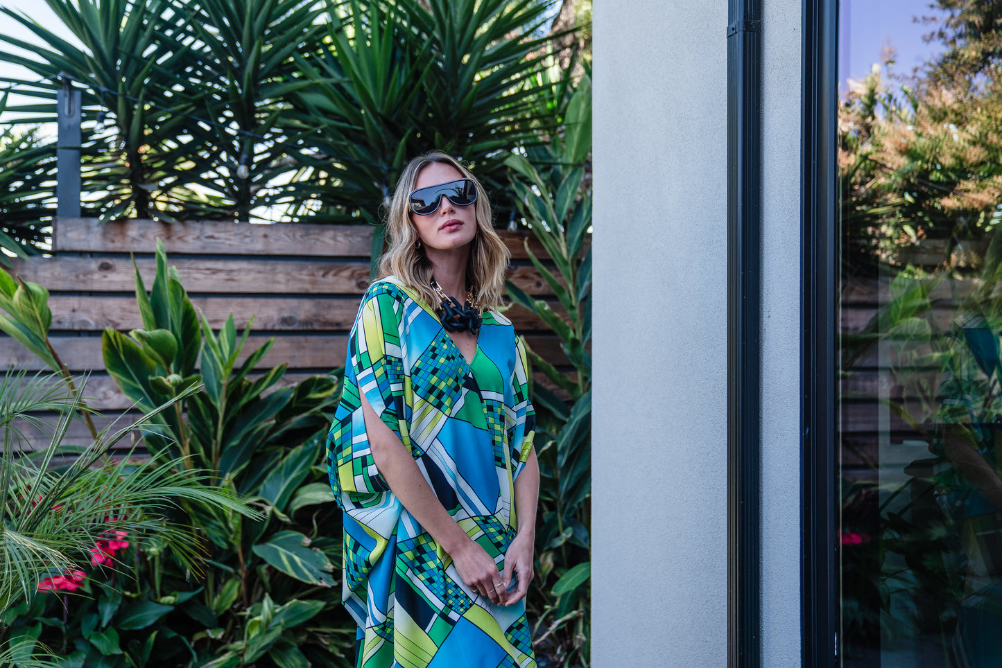 Jennafer Grace caftan in Pucci inspired mosaic print. Featuring an array of blue and green colors, this caftan features a deep v-neck, batwing sleeves, and ankle length hem.  