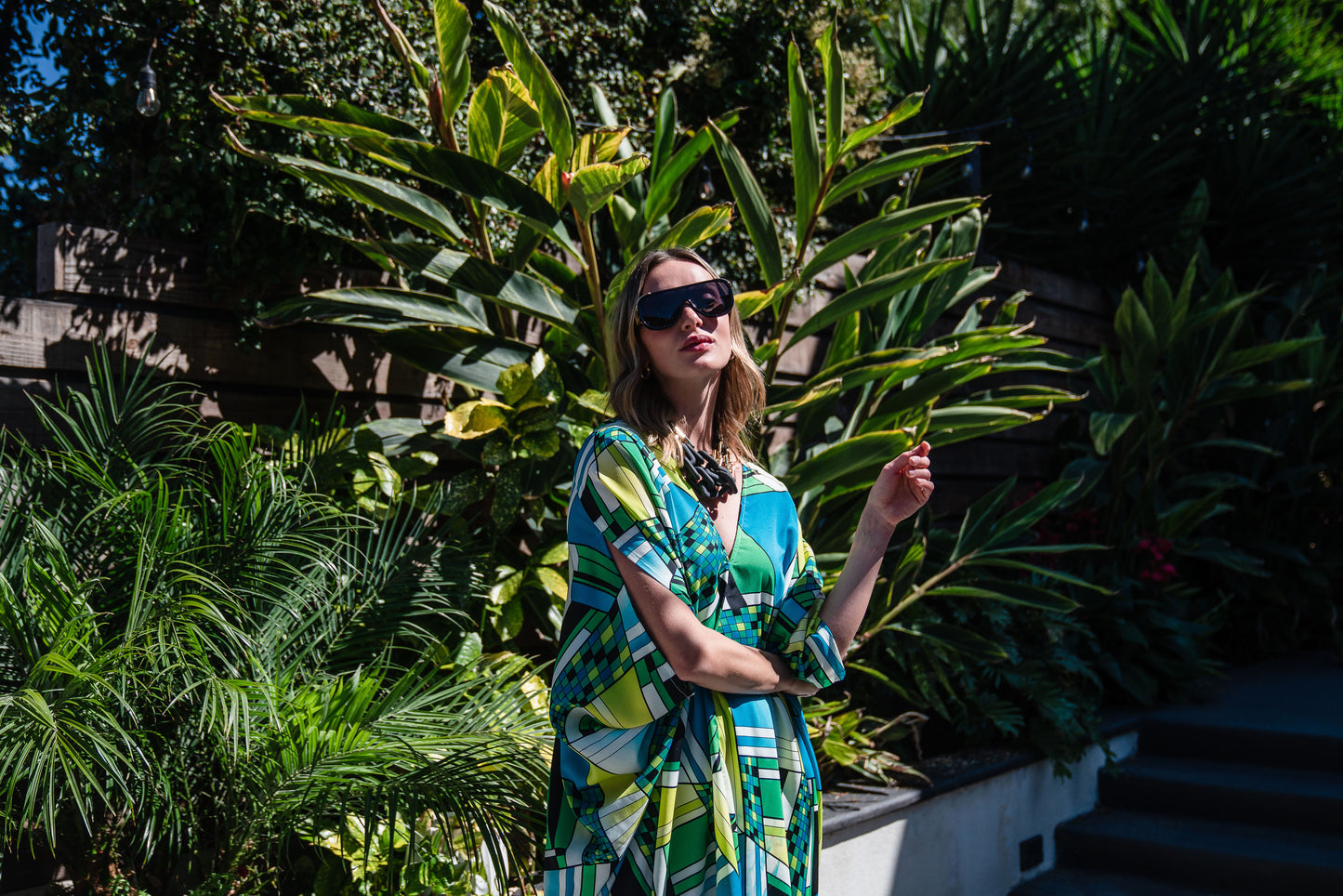 Jennafer Grace caftan in Pucci inspired mosaic print. Featuring an array of blue and green colors, this caftan features a deep v-neck, batwing sleeves, and ankle length hem.  