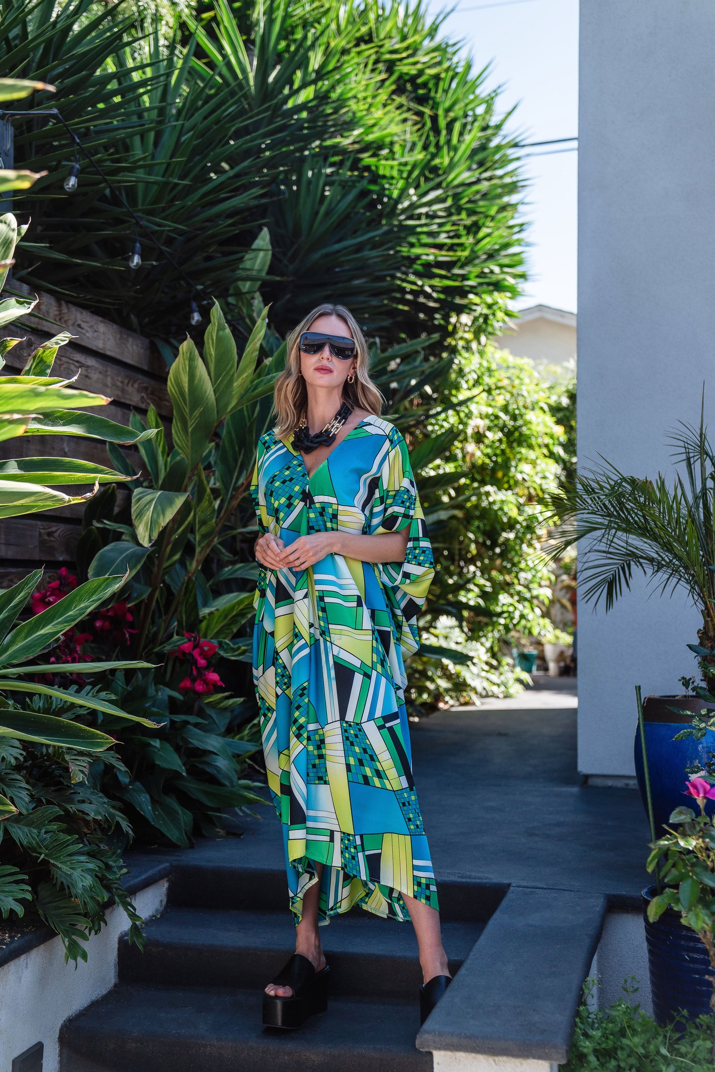 Jennafer Grace caftan in Pucci inspired mosaic print. Featuring an array of blue and green colors, this caftan features a deep v-neck, batwing sleeves, and ankle length hem.  