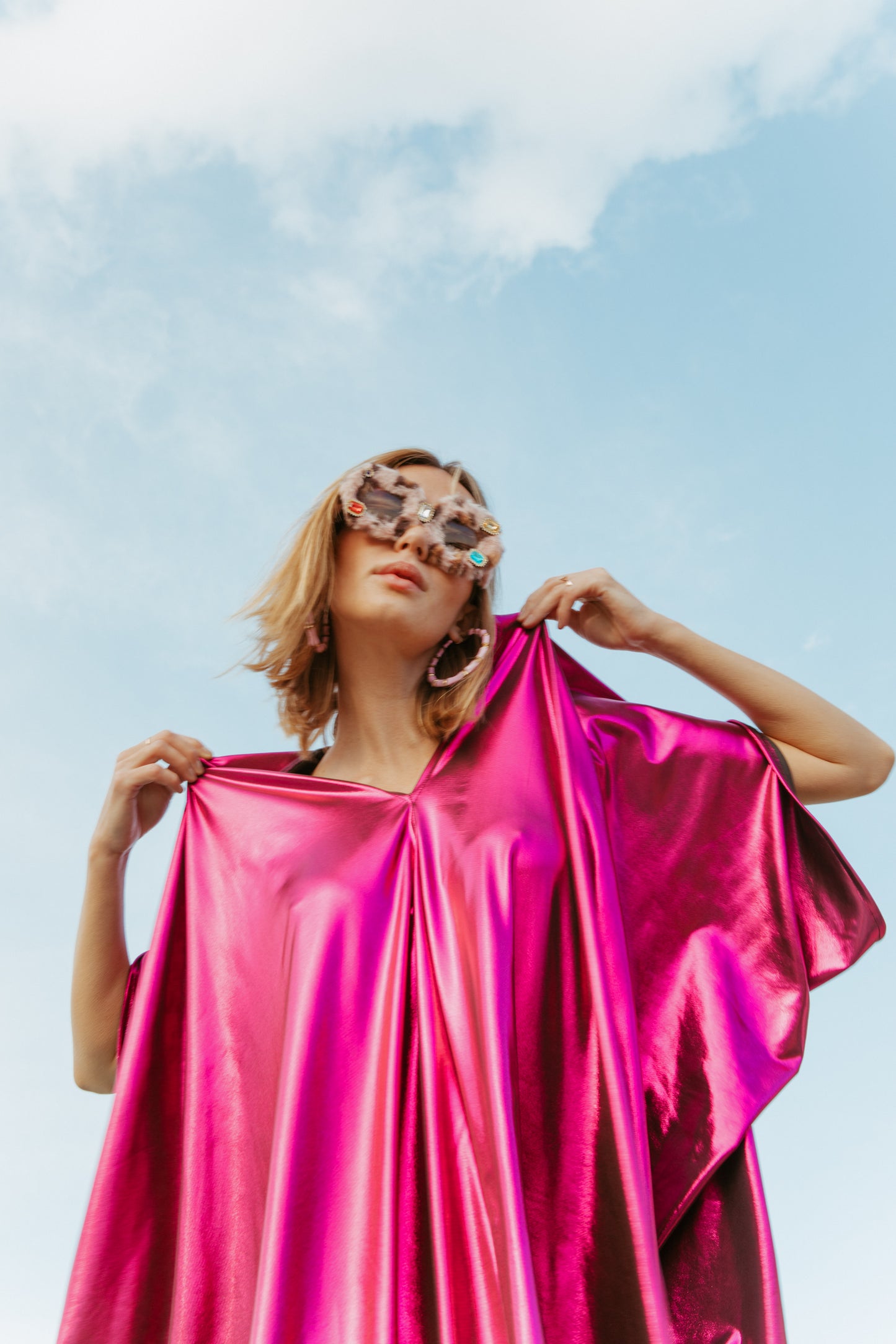 Bold, metallic caftan crafted from a slinky black jersey coated with a deep fuchsia foil that shimmers in the light. The caftan has a generous, free-flowing cut, with ample fabric creating an elegant, loose fit that drapes comfortably over the body, with batwing sleeves and a deep v-neckline.