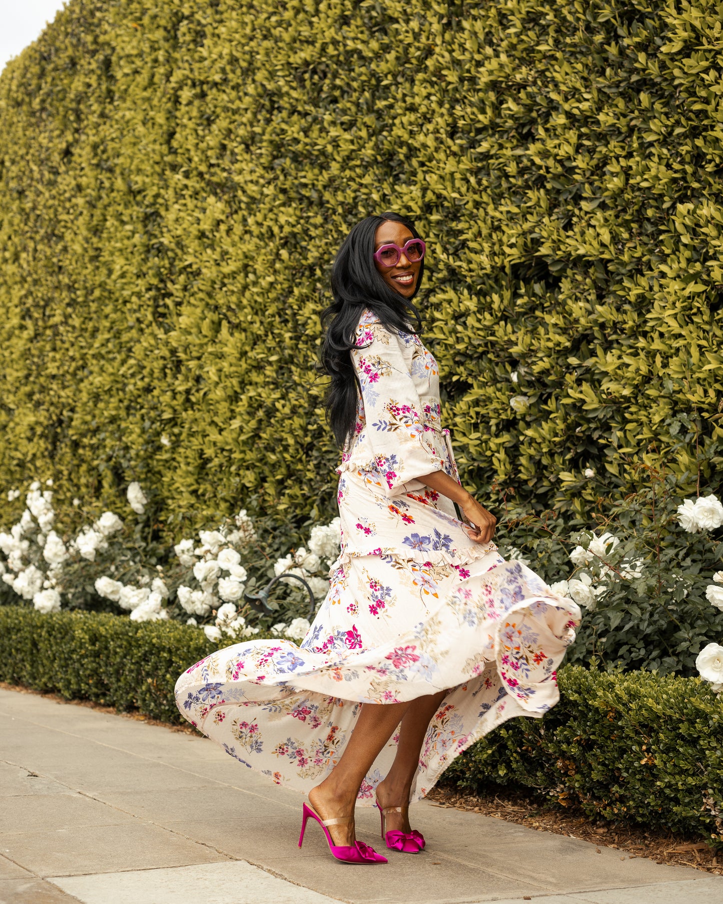 A floral maxi dress made from a soft, linen like crepe, it features high neck, bishop sleeves, tiered ruffle skirt and matching sash for a cinched waist. It's light, airy silhouette. Base color is pale yellow with a mixture of fuchsia, orange, and blue flowers as the print.