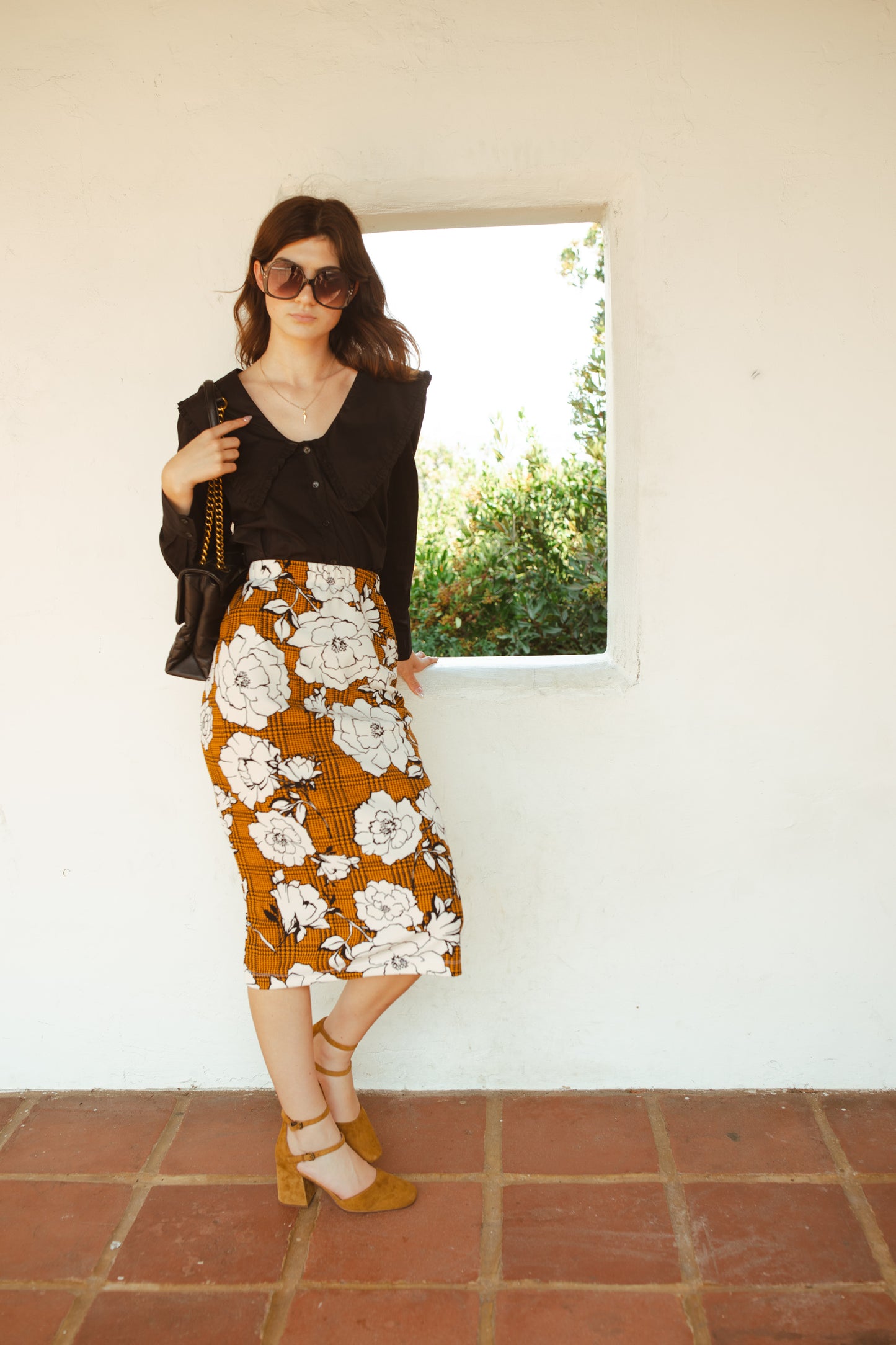 Cognac brown midi pencil skirt featuring black houndstooth pattern overlaid with large, modern, white and black floral print. This skirt is below the knee in length with an elastic waist for comfort. Bohemian floral meets dark academia in style.