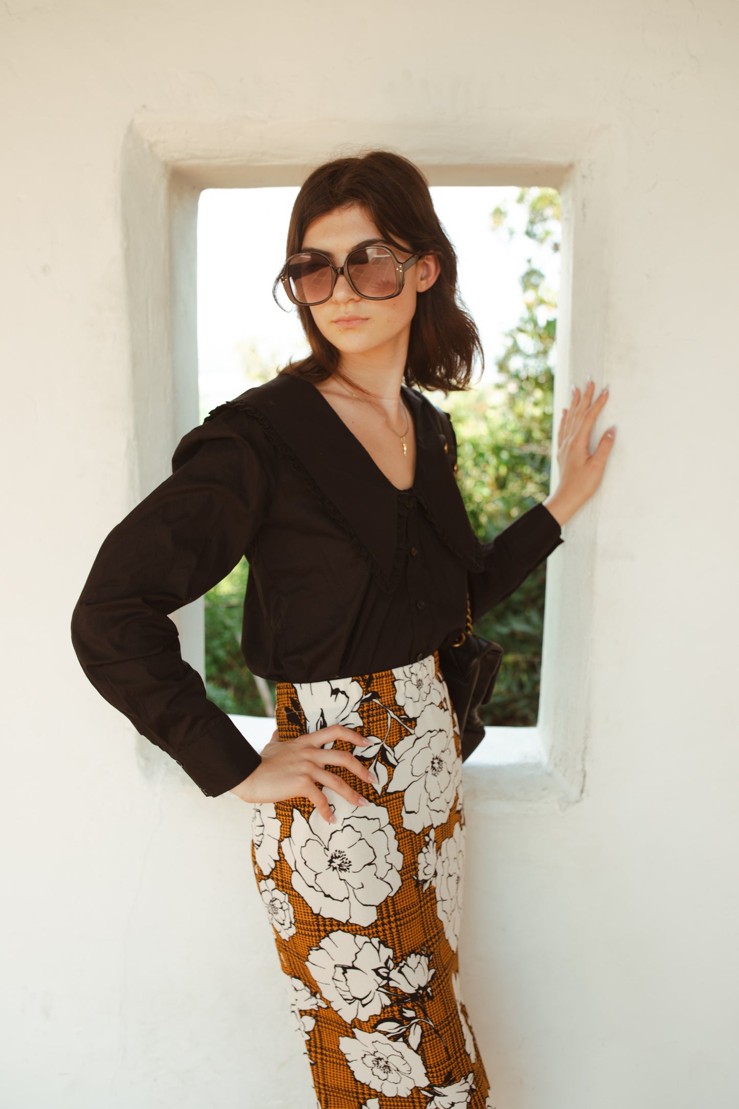 Cognac brown midi pencil skirt featuring black houndstooth pattern overlaid with large, modern, white and black floral print. This skirt is below the knee in length with an elastic waist for comfort. Bohemian floral meets dark academia in style.