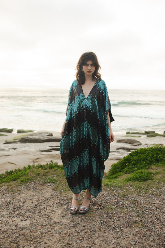 This Jennafer Grace caftan features and interchanging cerulean ocean blue and black sequins fabric with deep v-neckline, batwing sleeves, and ankle length hem. It is lined with a cotton jersey fabric for comfort. 