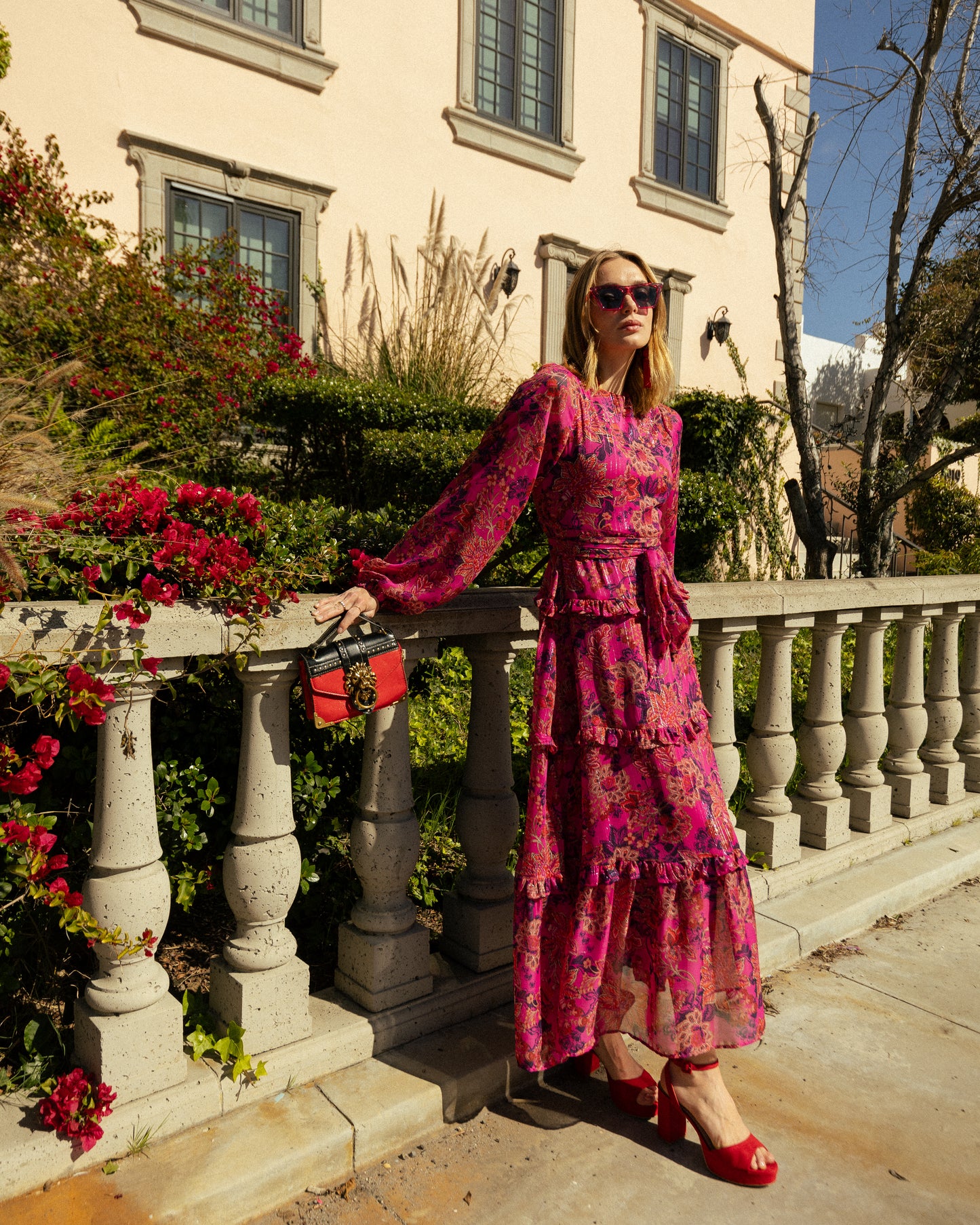 This floral maxi is crafted with a soft, metallic infused fabric, it features high neck, bishop sleeves, tiered ruffle skirt and matching sash for a cinched waist.