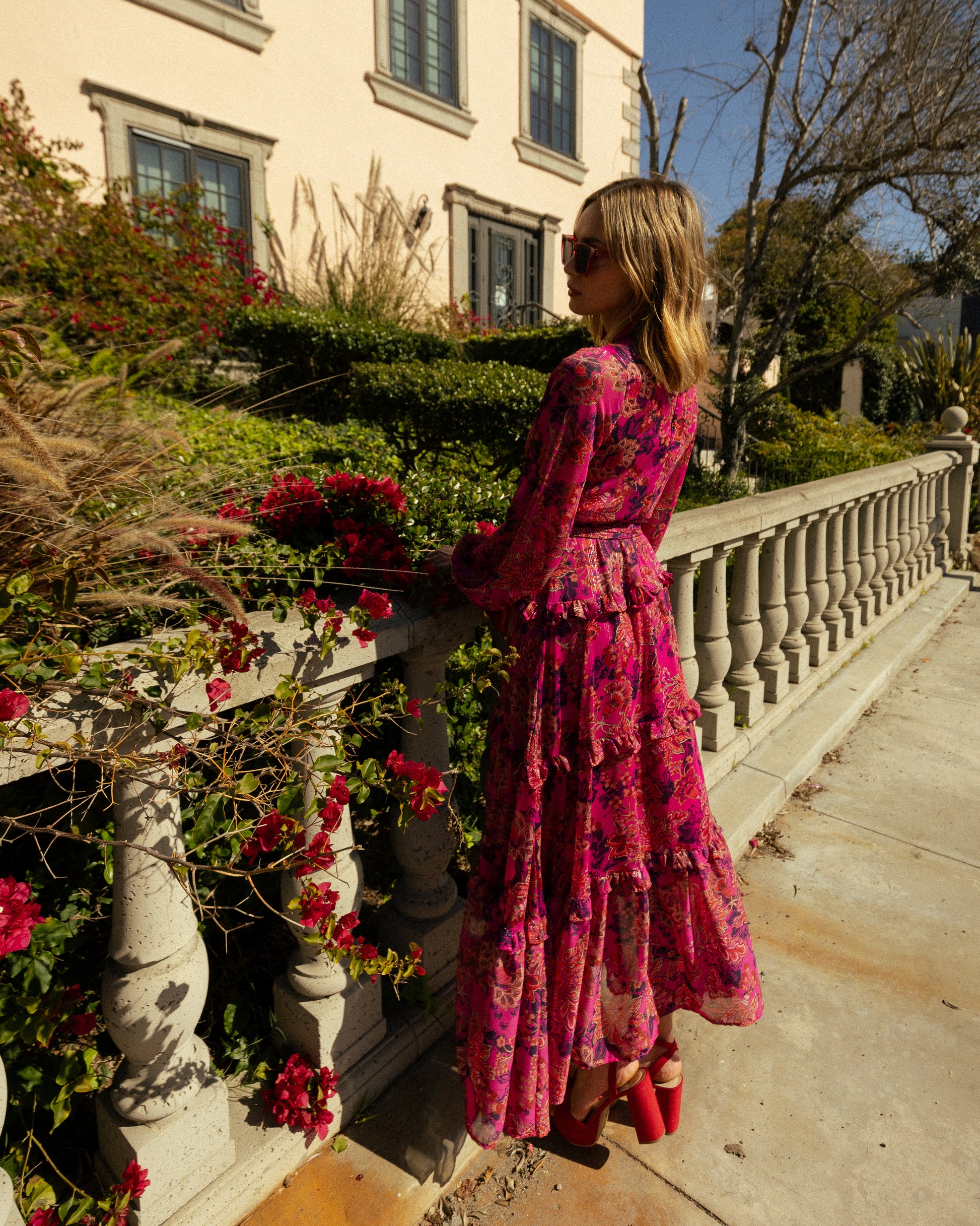 This floral maxi is crafted with a soft, metallic infused fabric, it features high neck, bishop sleeves, tiered ruffle skirt and matching sash for a cinched waist.