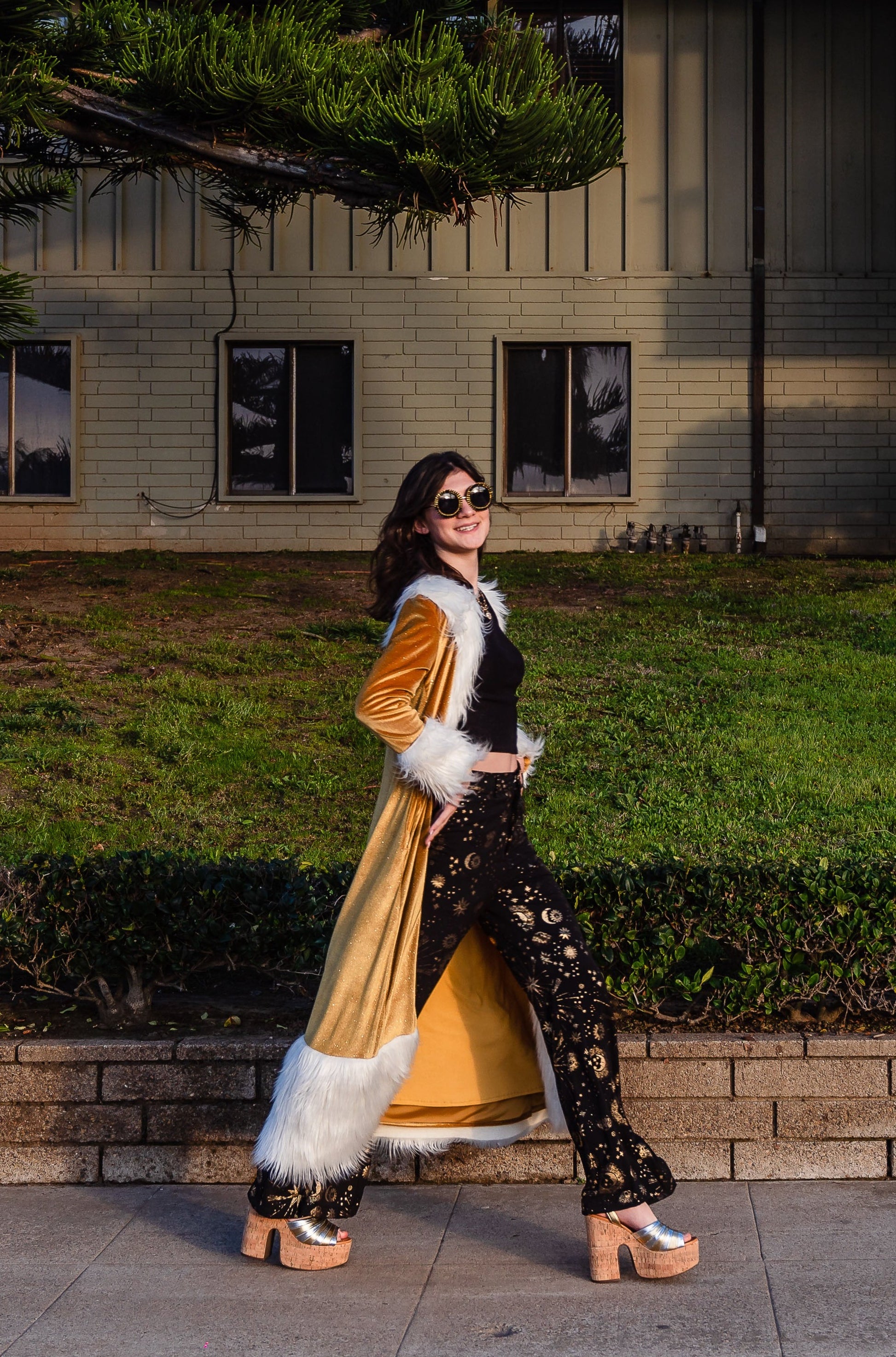 Long, penny lane style trench coat fashioned from a shimmering mustard gold velvet.Embellished with long, ivory white faux fur along collar, lapel, cuffs, and hem. Retro 70s aesthetic.
