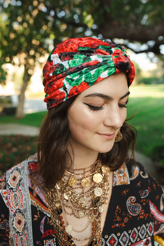 Red, green, white and black impressionist floral stretch velvet fashion turban hat that wears similar to a beanie, with ruching of the fabric that meets front and center at an elegant knot. Vintage-inspired retro 1920s mixed with a modern fabric.