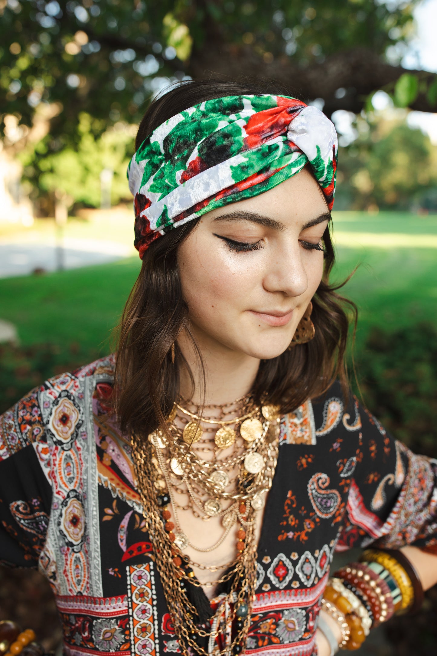 White, green, and red abstract floral print velvet headband with a front twist.